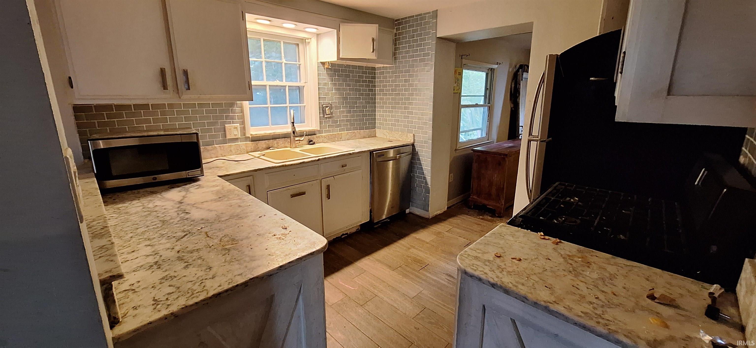 Kitchen featuring light-toned countertops, white cabinetry, and a subway tile backsplash