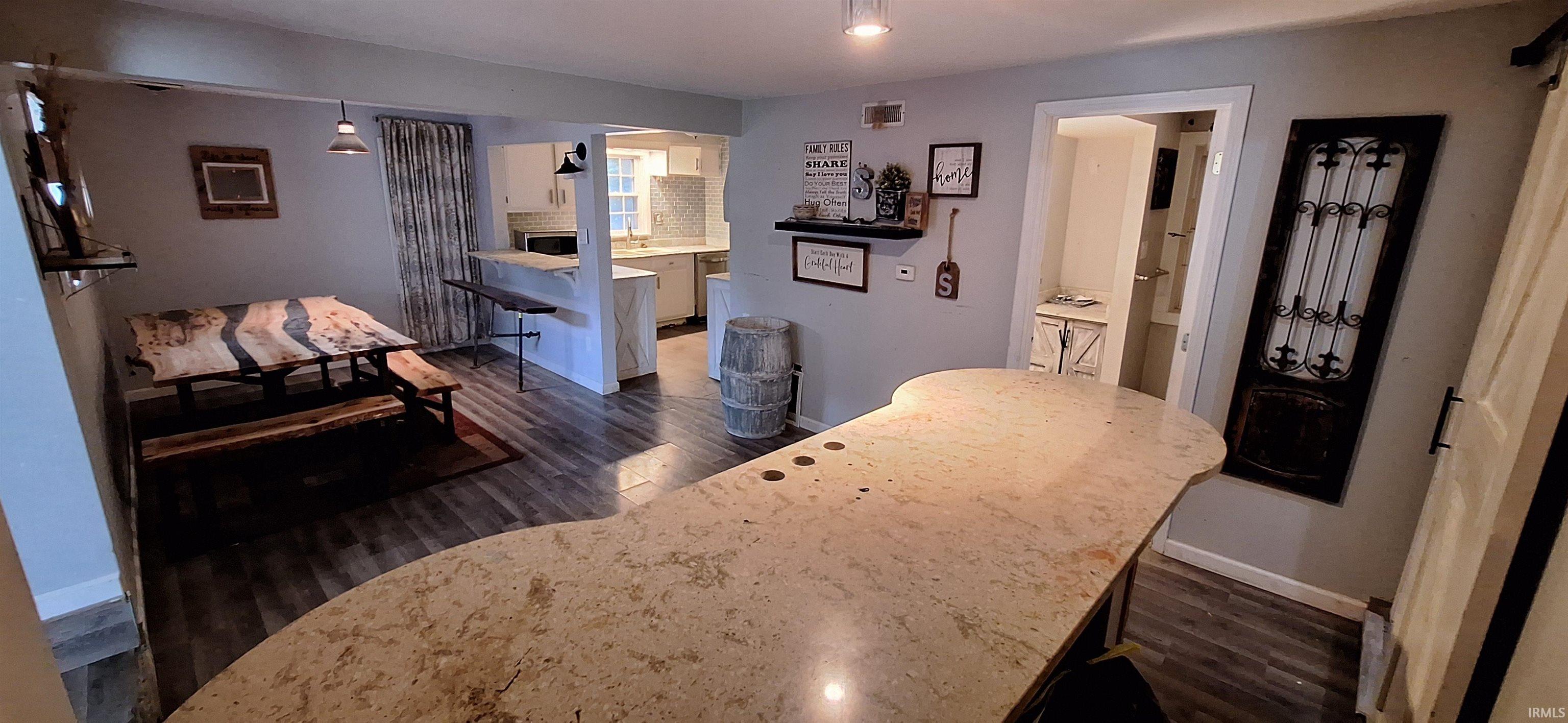 Spacious room featuring wood-finish flooring, a large island with a light-toned countertop, and a defined dining area