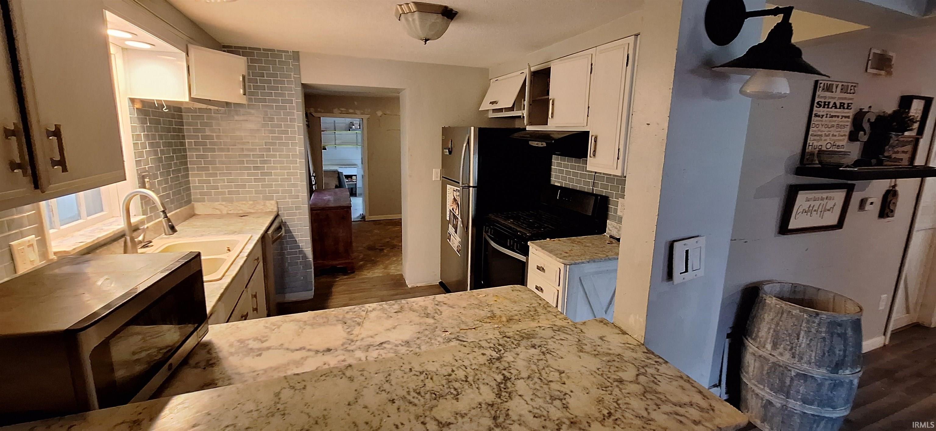 Kitchen featuring a variegated countertop island, white cabinetry, and a subway tile backsplash