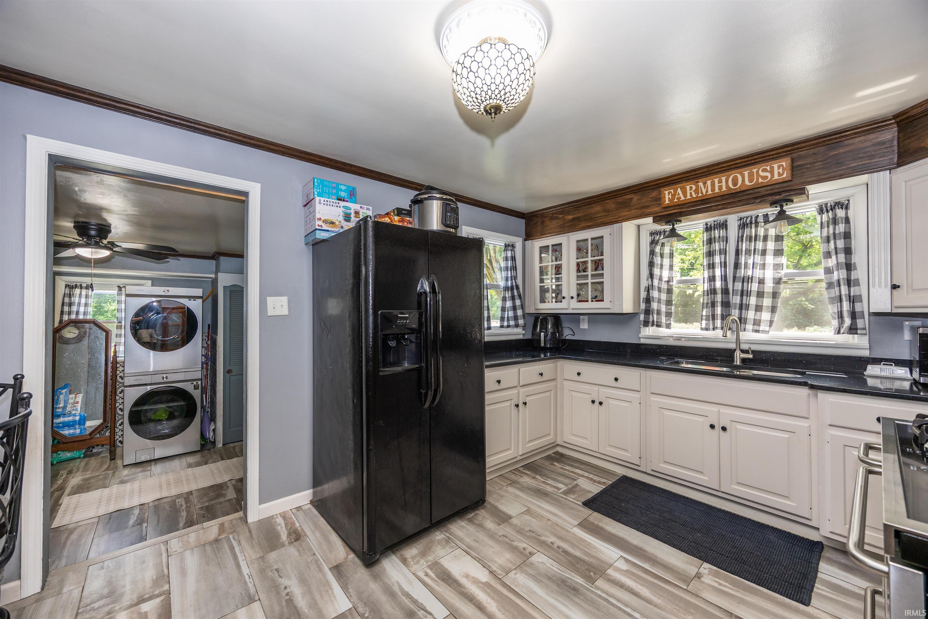 Kitchen featuring wood-finish flooring, white cabinetry, dark countertops, and a stainless steel sink