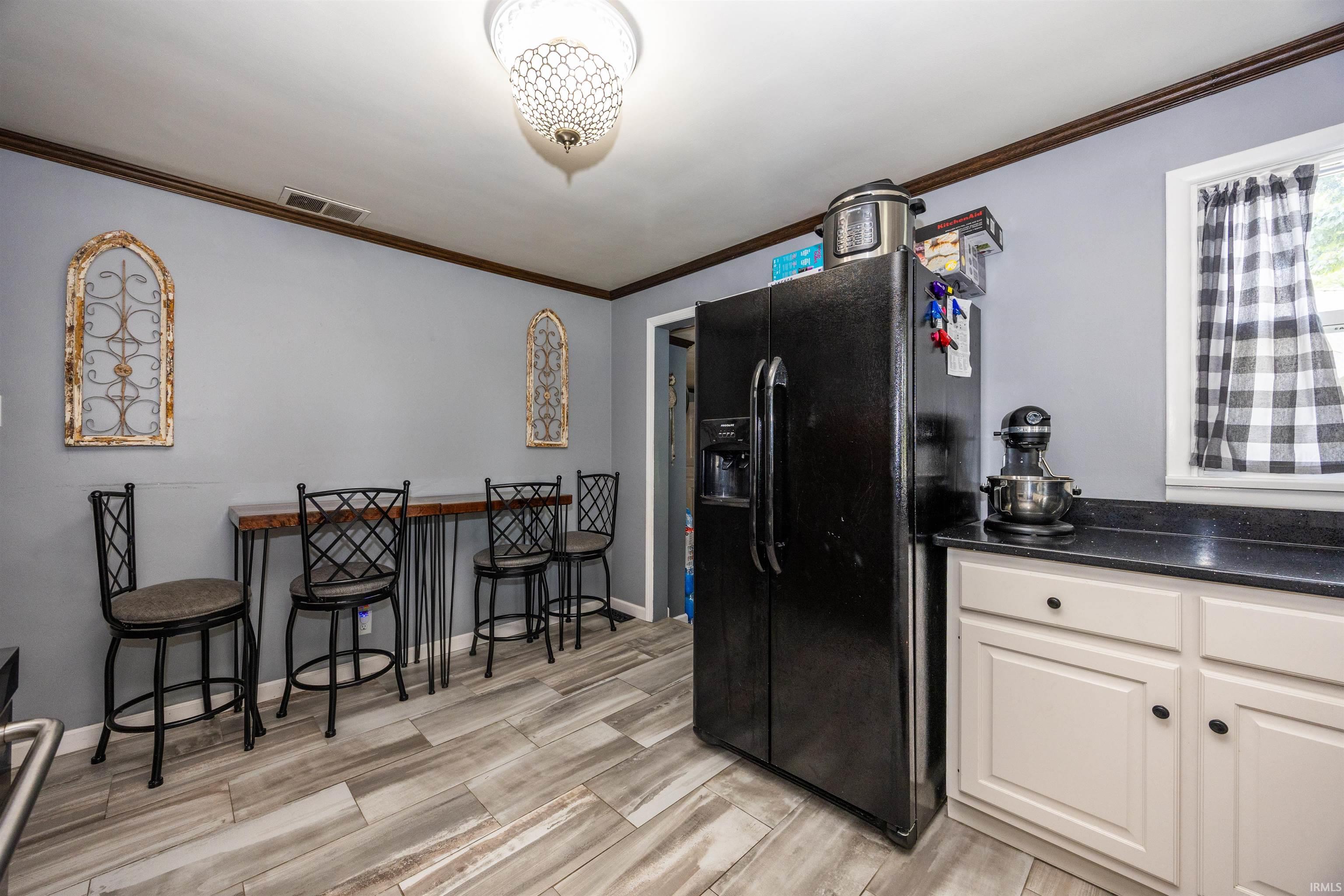 Kitchen area featuring wood-finish flooring, white cabinetry, dark countertops, and a black side-by-side refrigerator