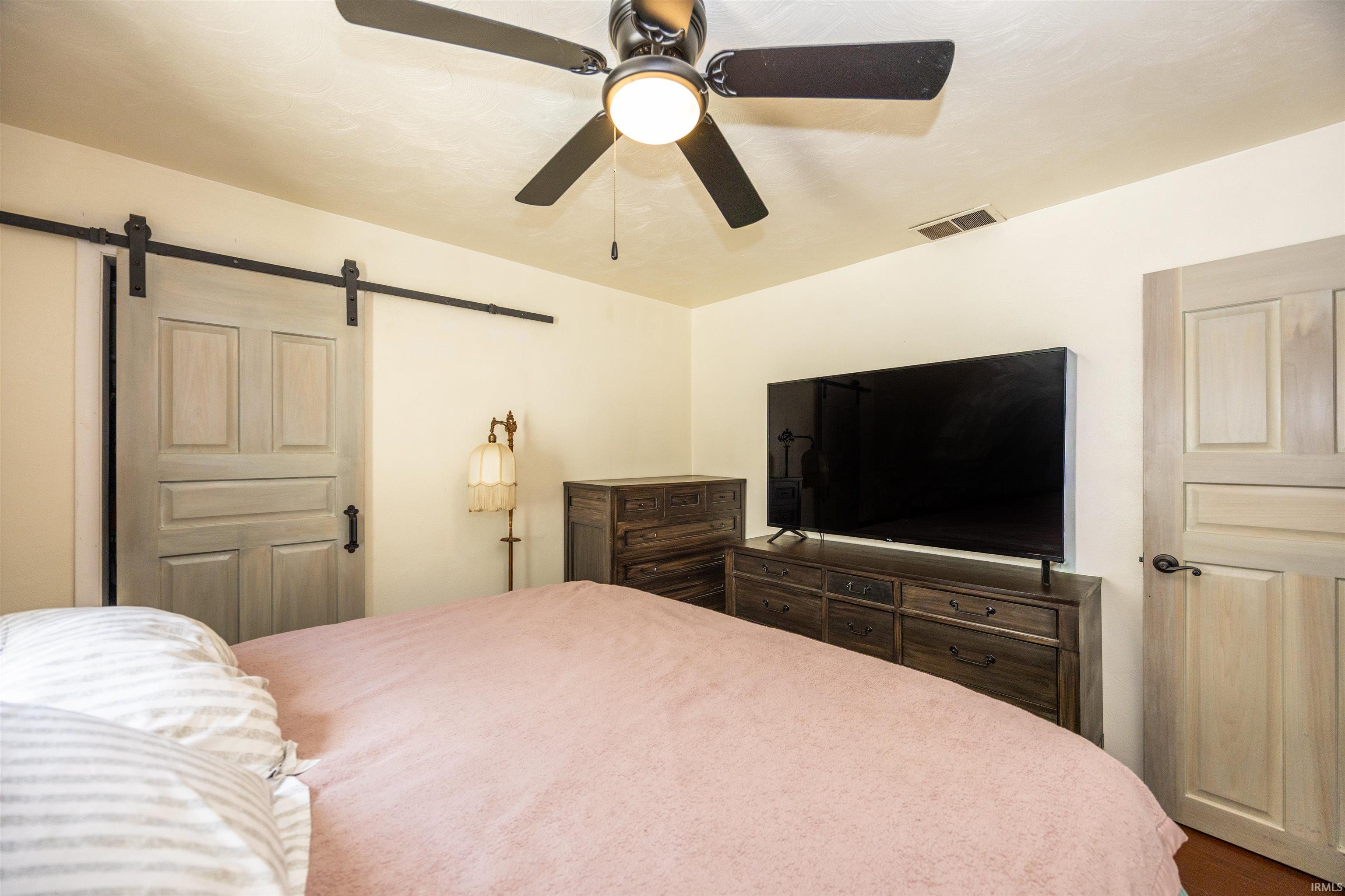 Ceiling fan with integrated lighting, a panel door with black hardware, and a barn door with a black track