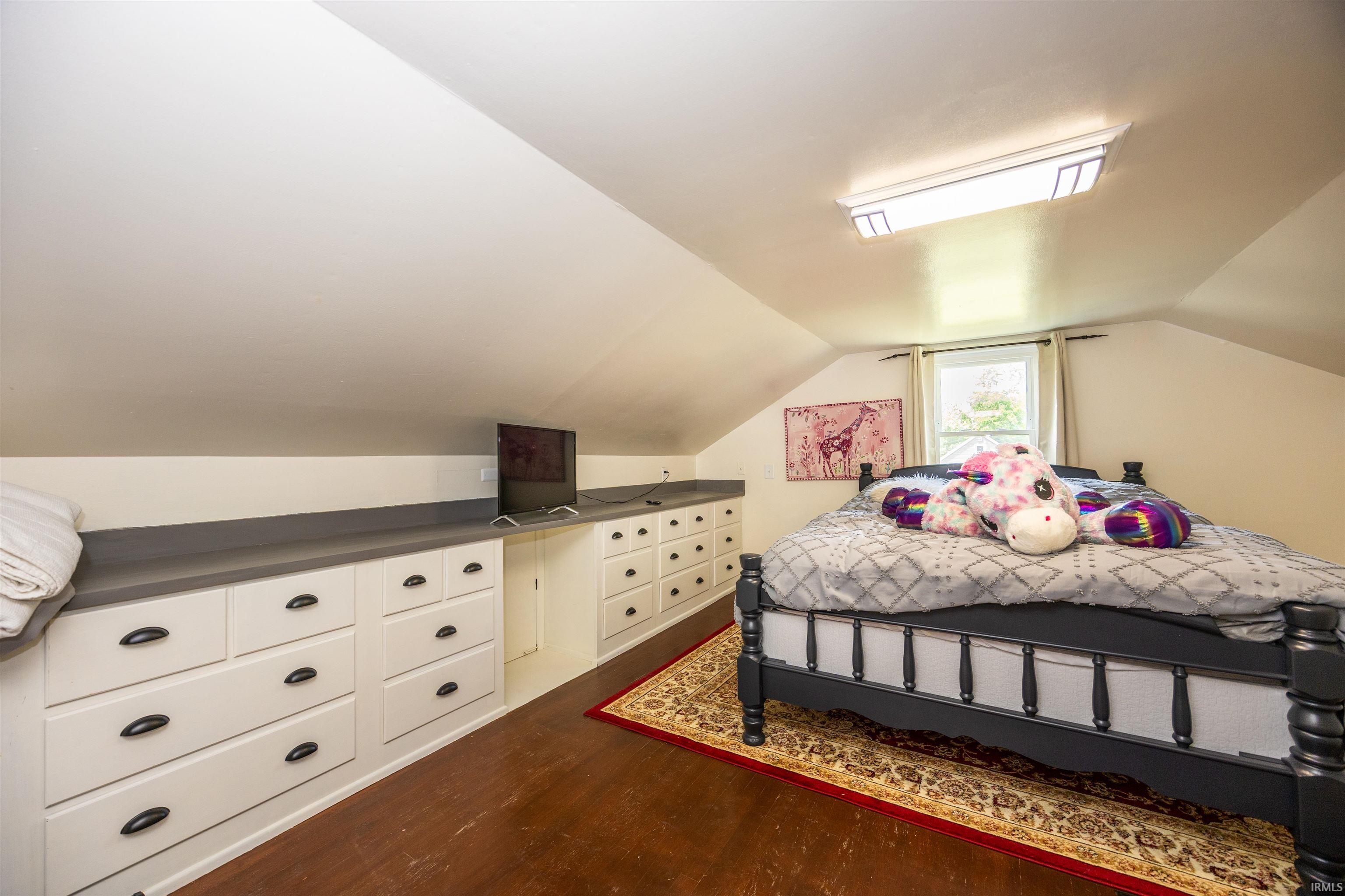 Attic space featuring wood-finish flooring and a vaulted ceiling with a skylight