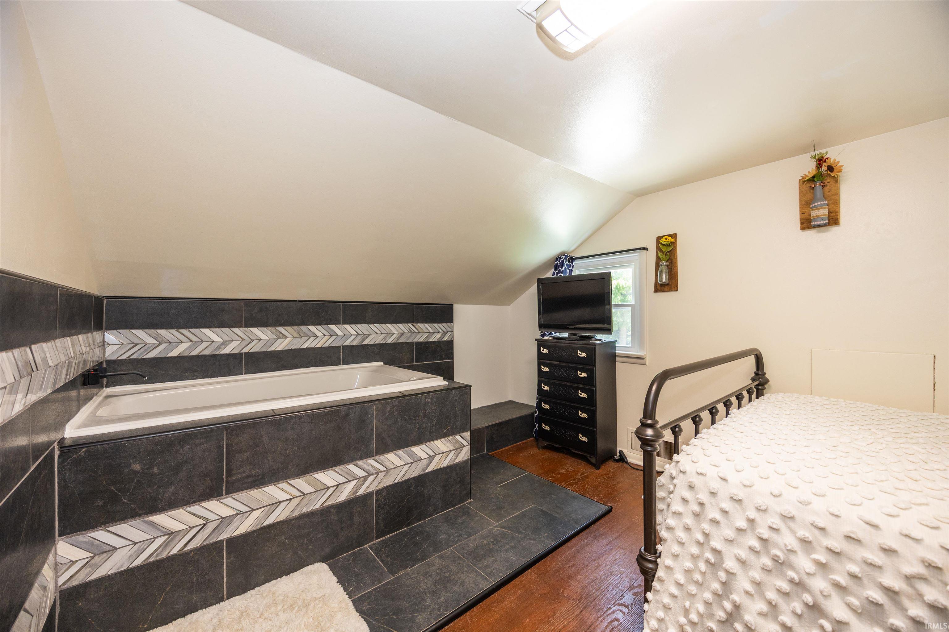Built-in soaking tub featuring dark tile surround with decorative chevron accent banding