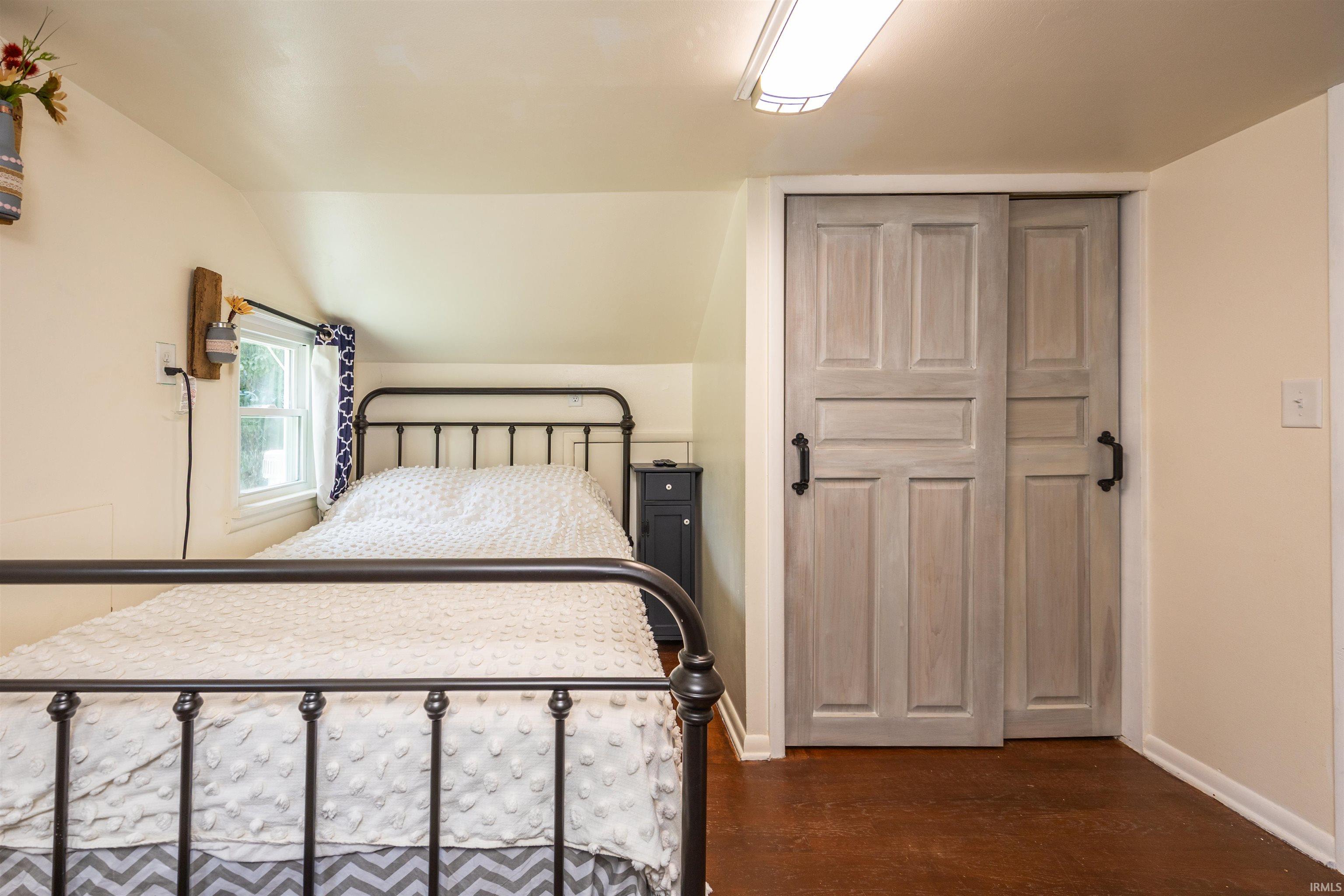 Sliding barn-style closet doors with black hardware, wood-finish flooring, and white walls