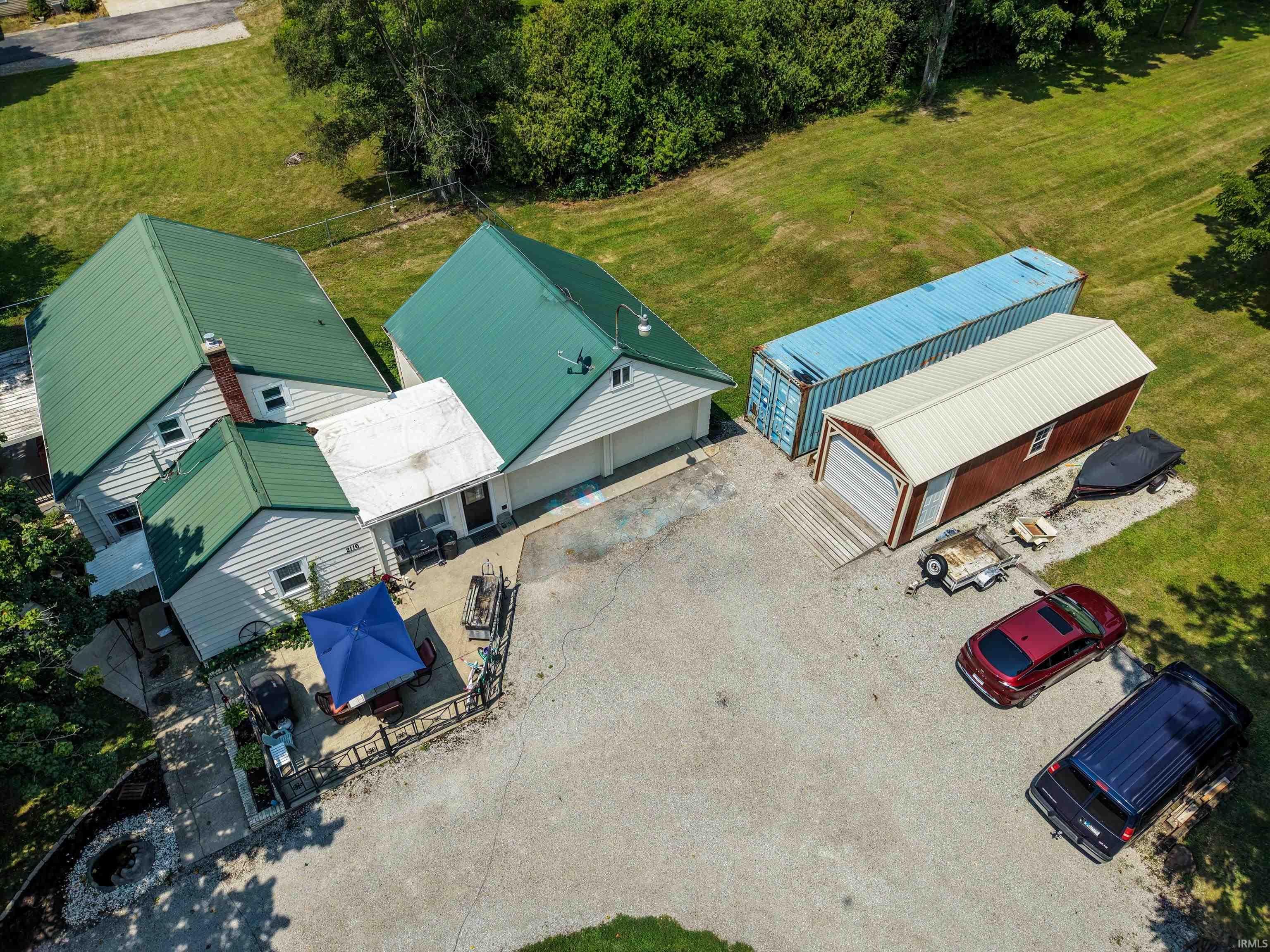 Property featuring multiple green metal roofs, an attached two-car garage, and an additional detached outbuilding