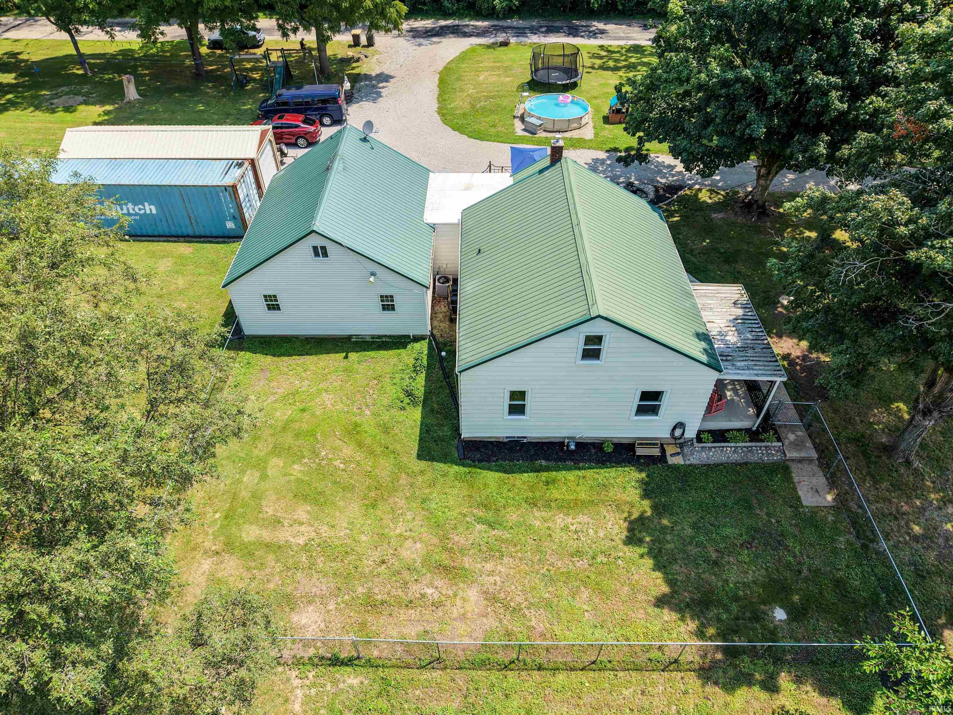 Two-structure property featuring light-colored siding and green metal roofing