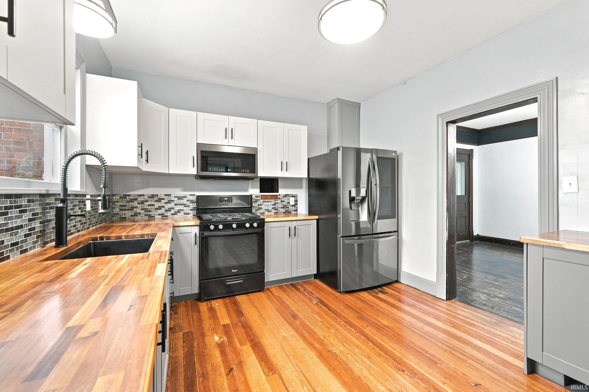 Kitchen featuring wood-finish countertops, mosaic tile backsplash, and stainless steel appliances