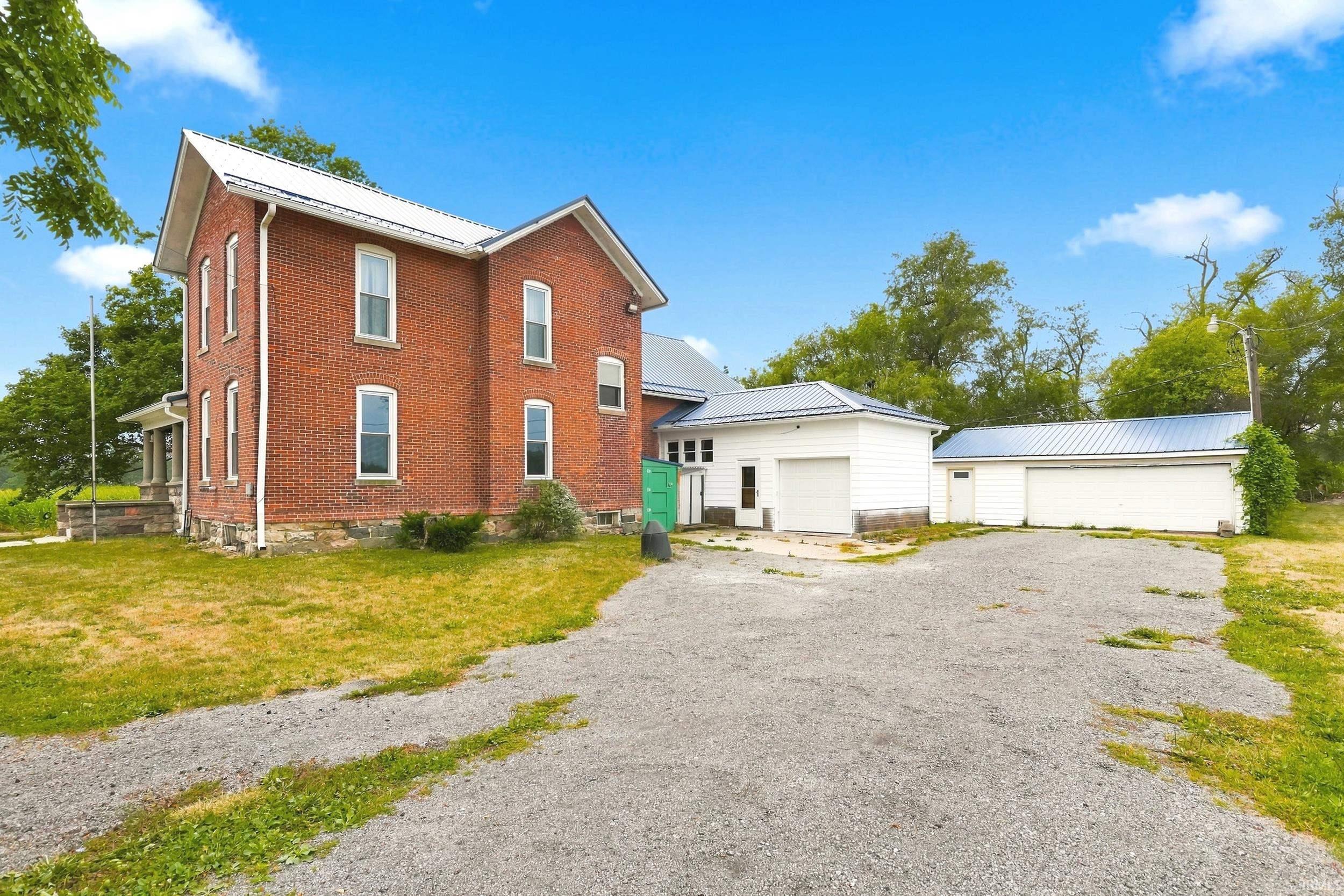 Traditional brick residence featuring a metal roof and a gravel driveway