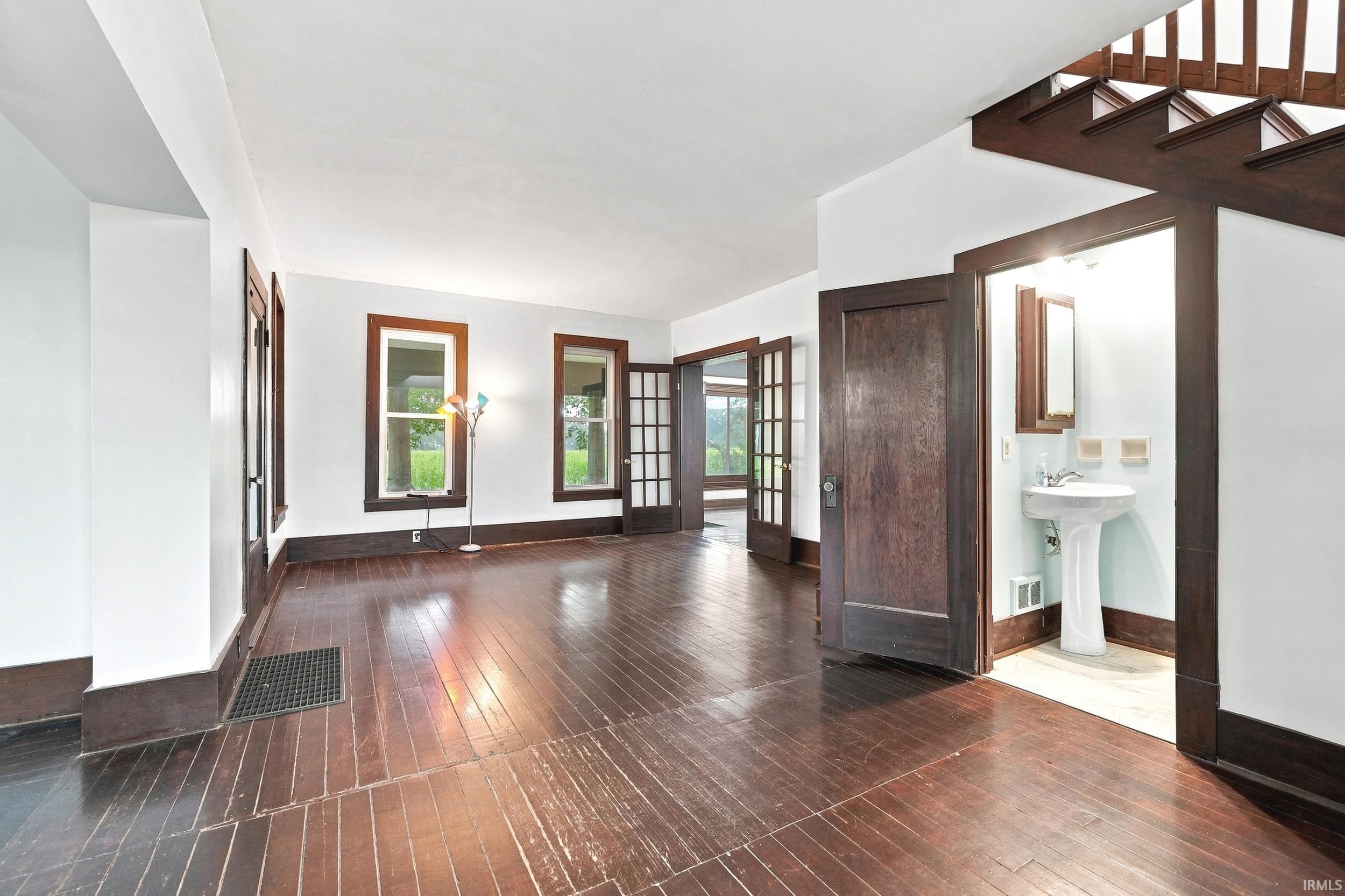 Spacious room featuring dark wood-finish flooring, white walls, and dark wood trim