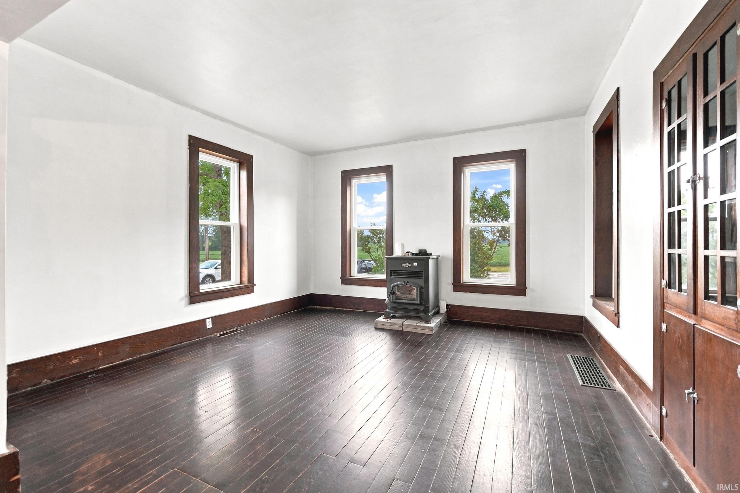 Room featuring dark wood-finish flooring, white walls, and dark wood trim