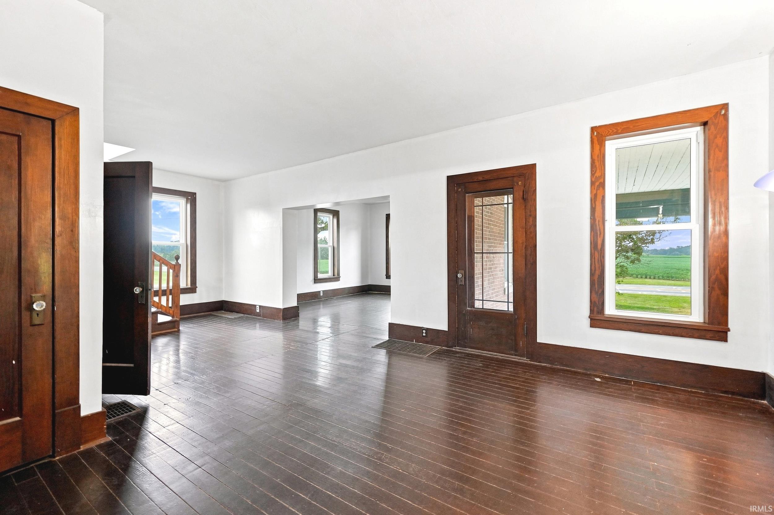 Expansive interior space featuring wood-finish flooring, white walls, and dark wood trim