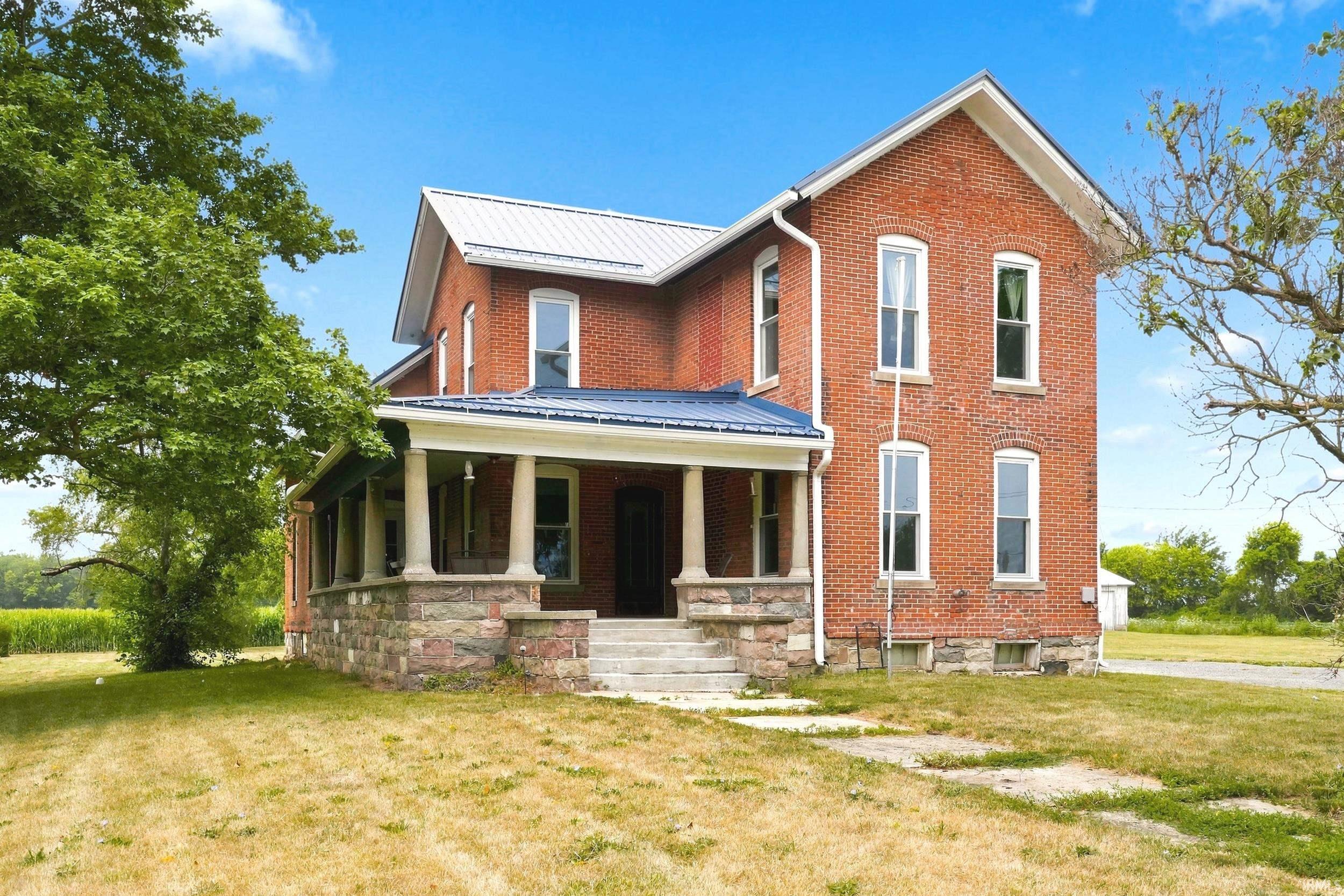 Brick-clad residence featuring a covered front porch with stone columns and foundation