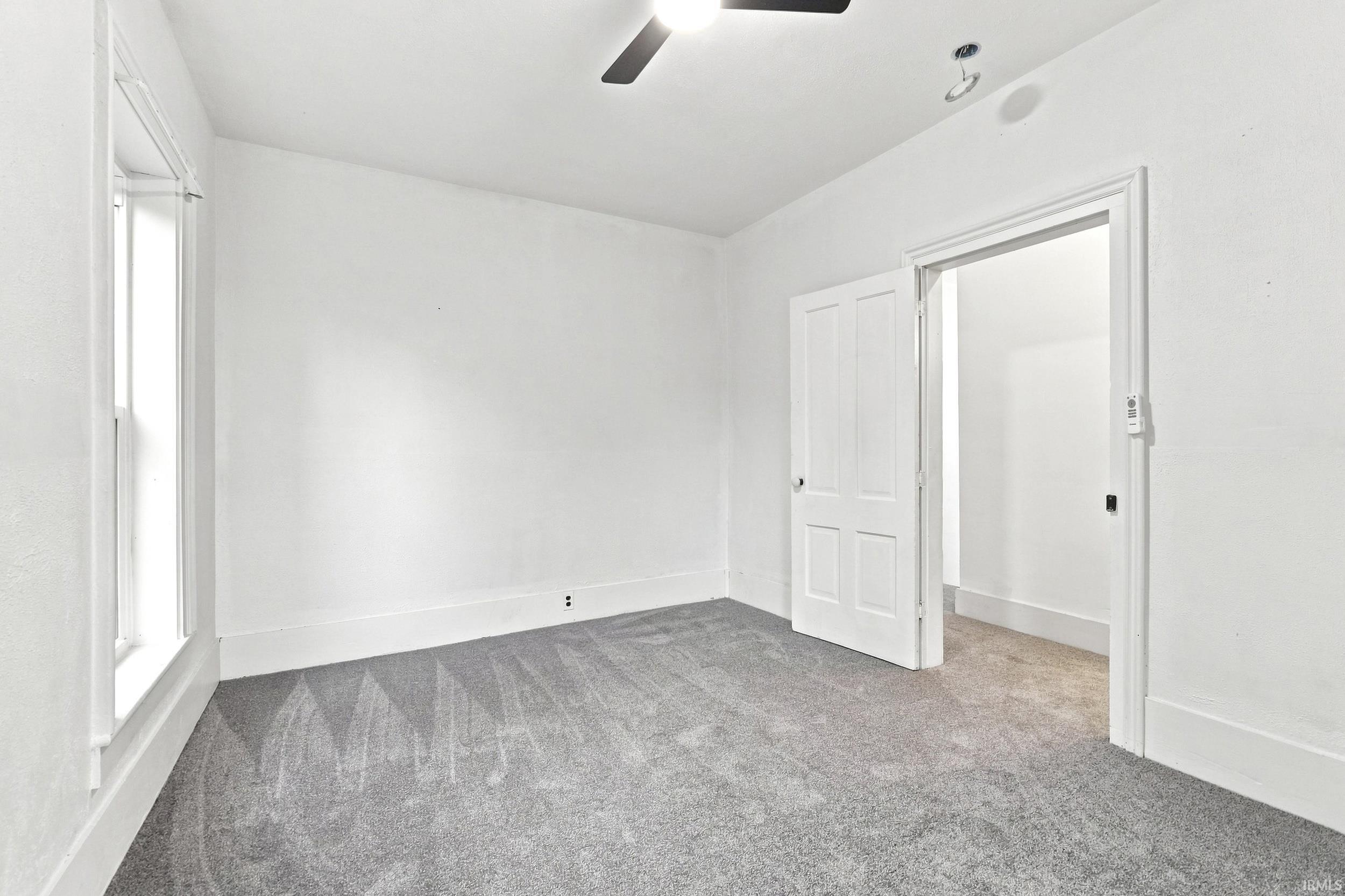 Room featuring a ceiling fan, light gray carpeting, crisp white walls, and a window with white trim