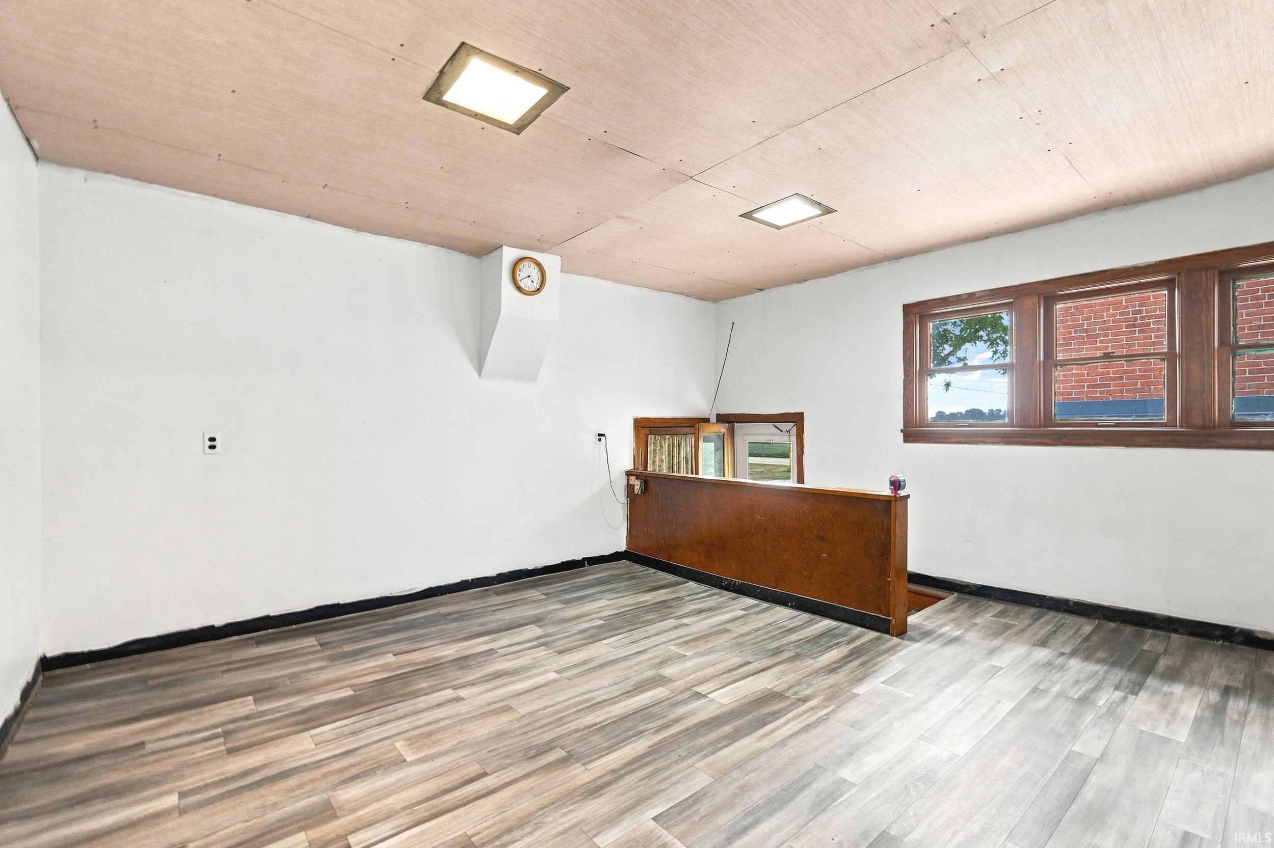 Spacious interior featuring wood-finish flooring, white walls, and a light wood ceiling