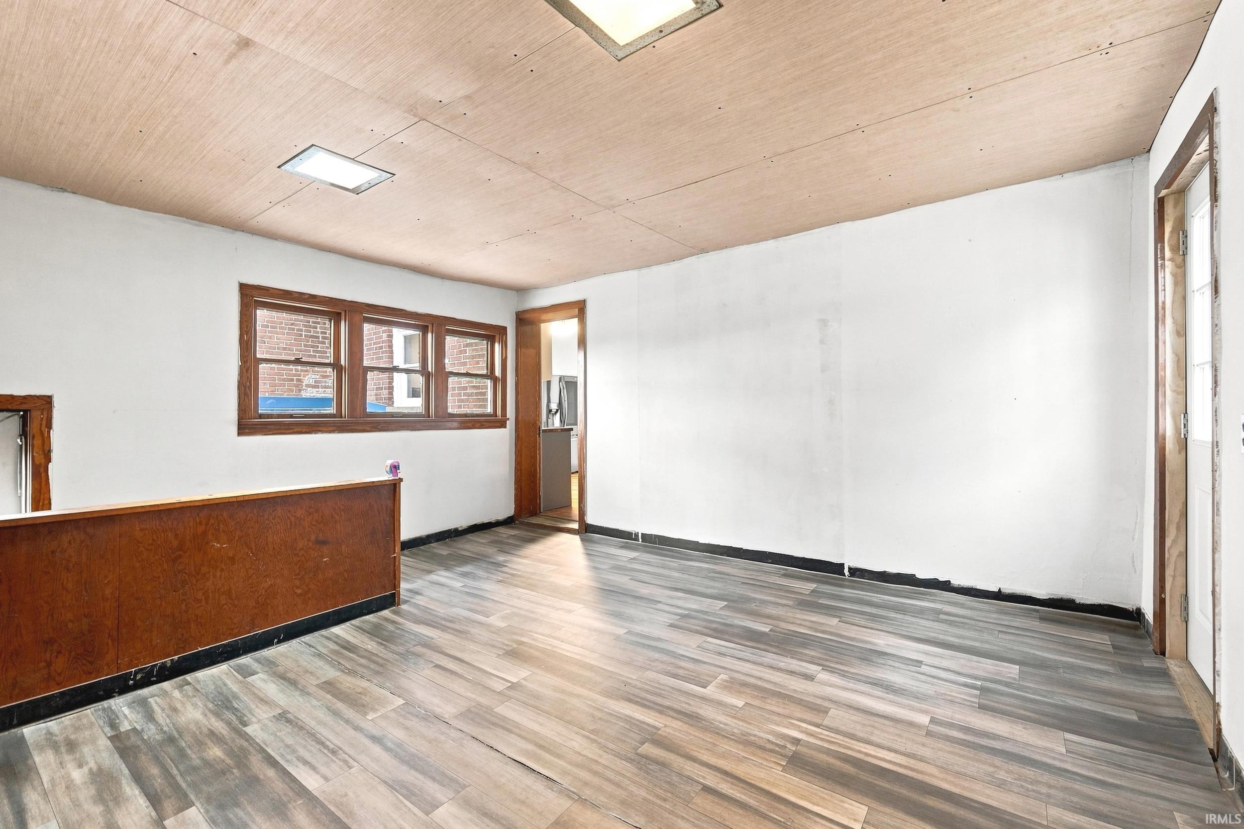 Spacious room featuring wood-finish flooring and a wood-paneled ceiling