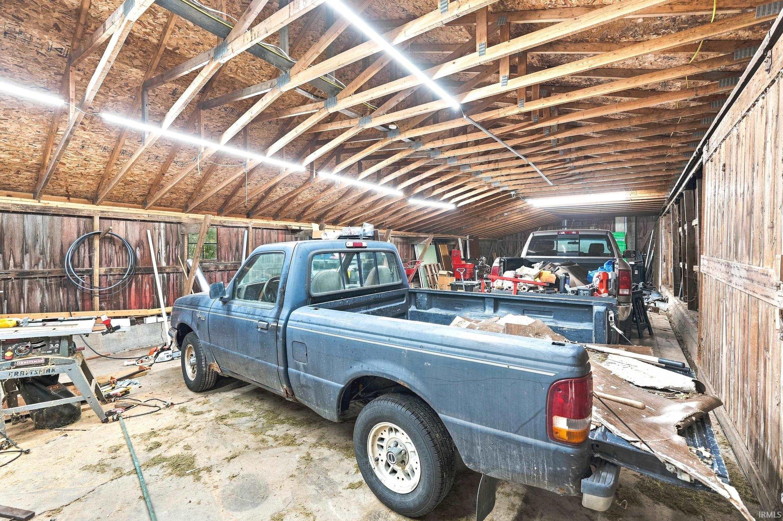 Spacious outbuilding featuring exposed wood beam construction, durable OSB roofing, and ample task lighting