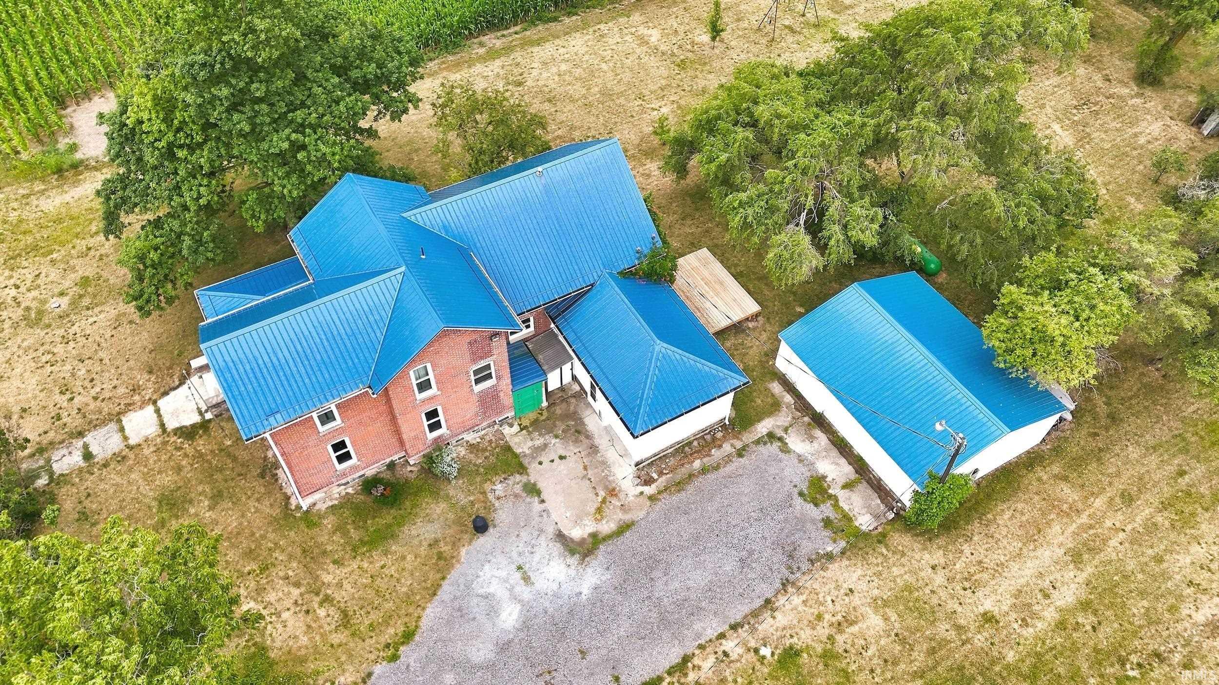 Brick residence featuring a blue metal roof and multiple gables