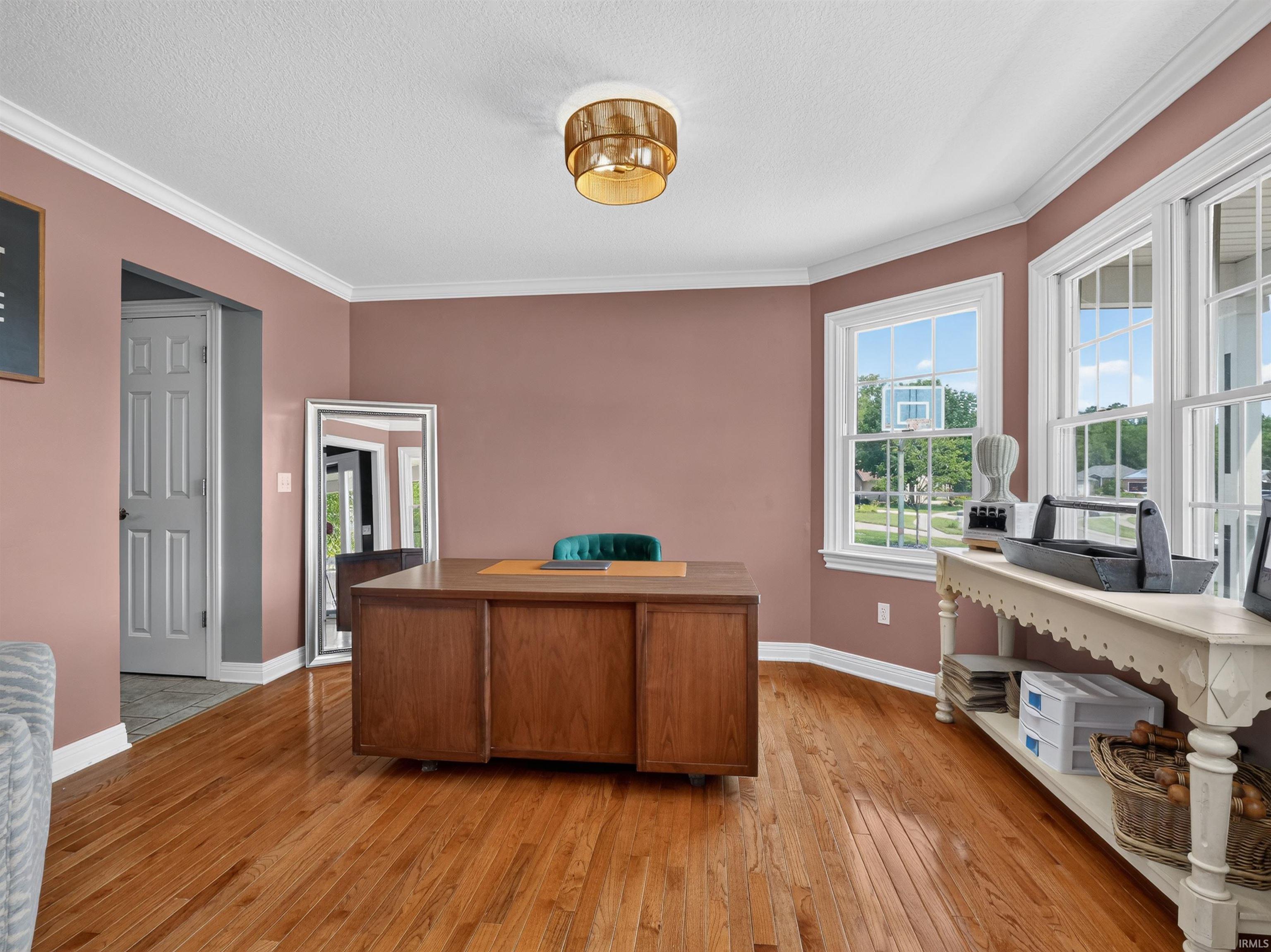 Wood-finish flooring with crown molding and a built-in wooden desk