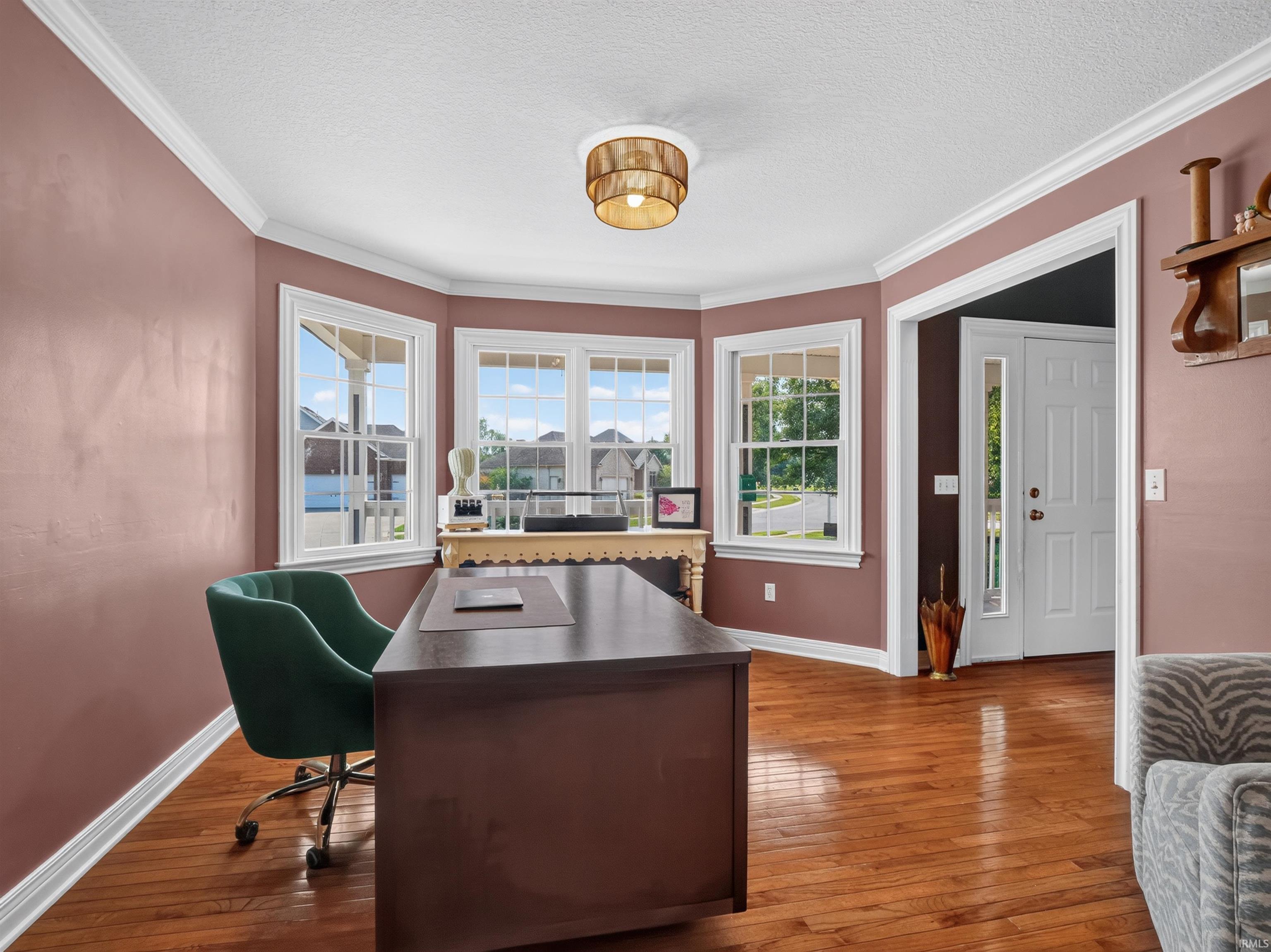 Bay window configuration, multiple grid-pattern windows, wood-finish flooring, crown molding, and substantial baseboards