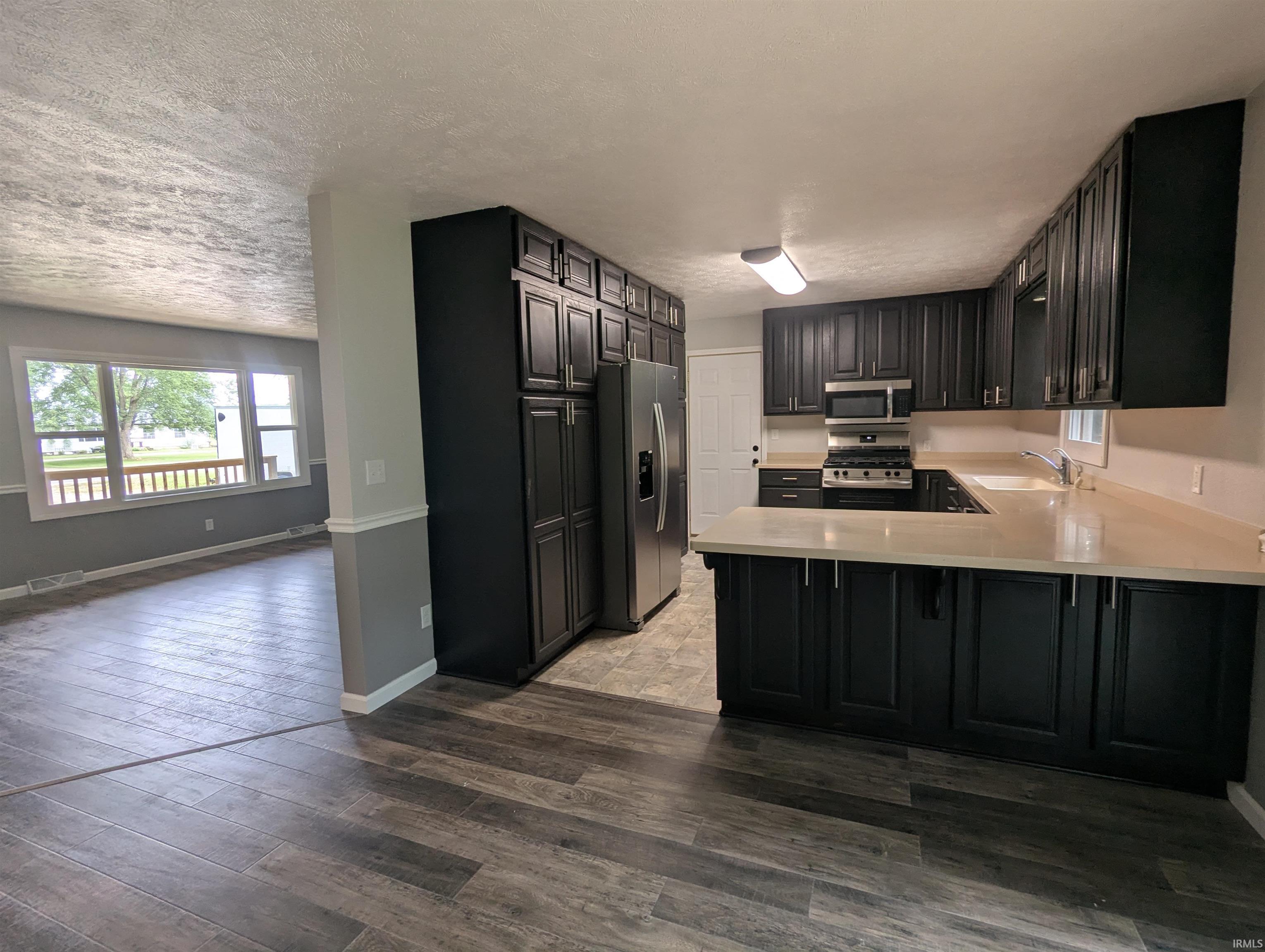 Kitchen featuring dark cabinetry, light countertops, and stainless steel appliances