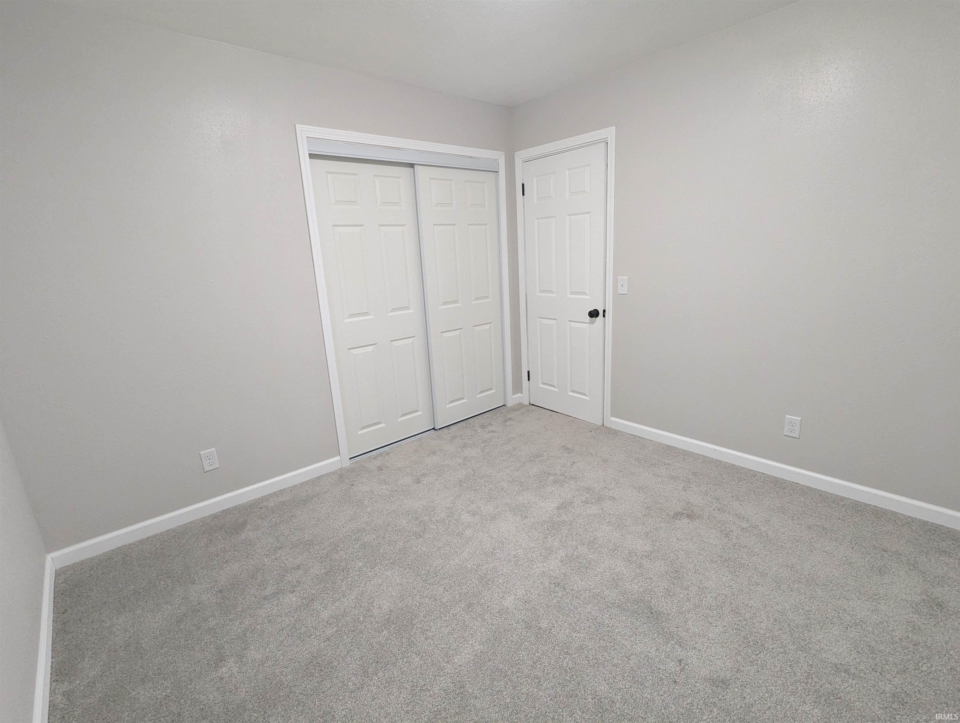 Room featuring light gray wall paint, gray carpet flooring, white baseboards, and white trim around doorways