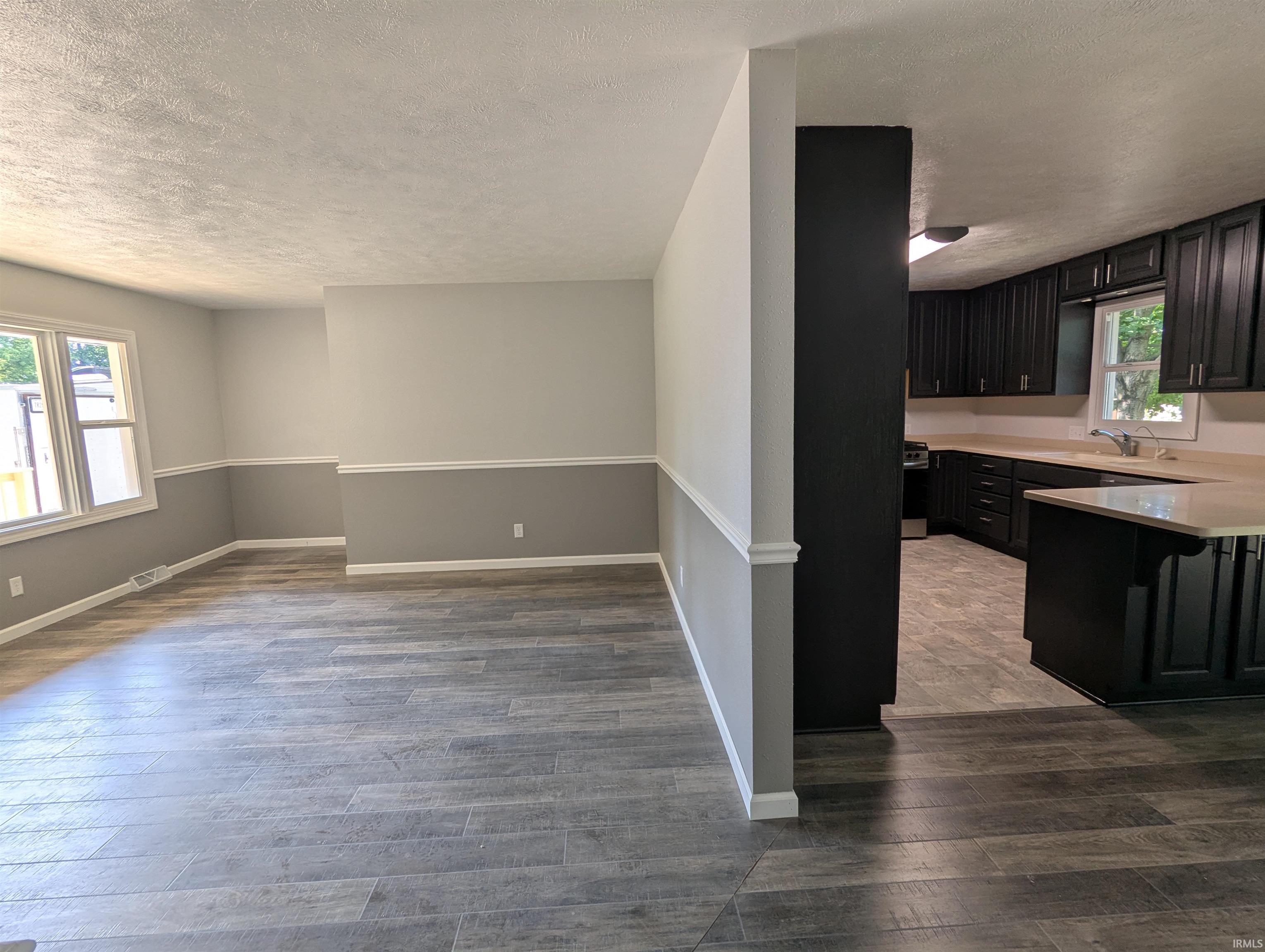 Open-concept living space featuring wood-finish flooring and two-tone wall treatment with chair rail molding