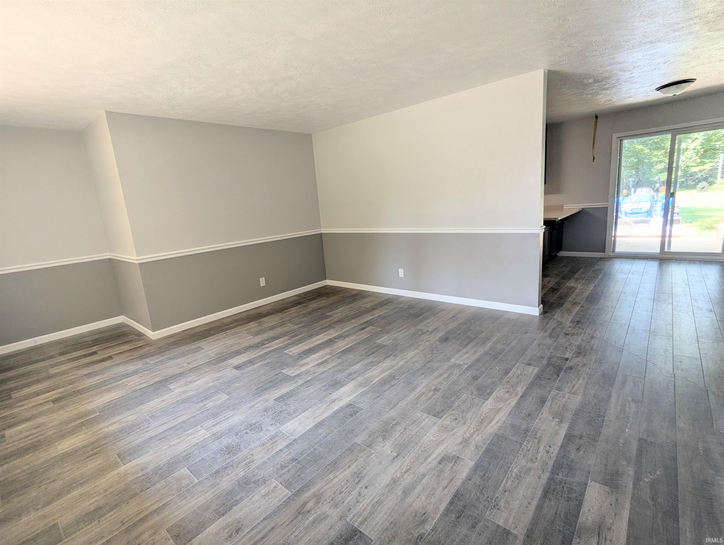 Spacious interior room featuring light wood-finish flooring, two-tone wall paint, and white trim
