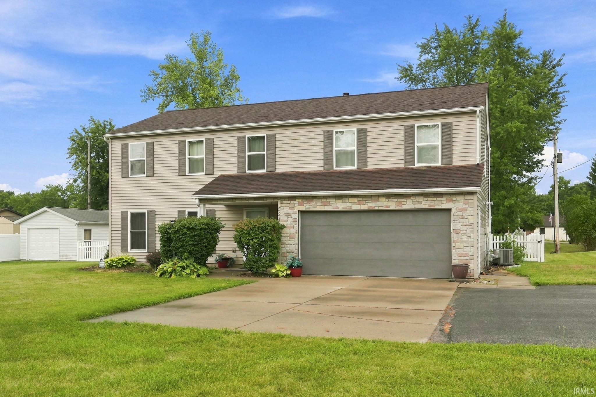 Two-story residence featuring light-colored siding and a stone-clad garage