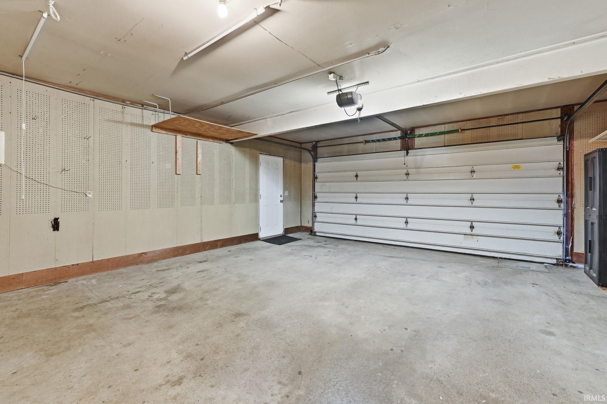 Spacious garage featuring a concrete floor, overhead lighting, and an automatic garage door opener