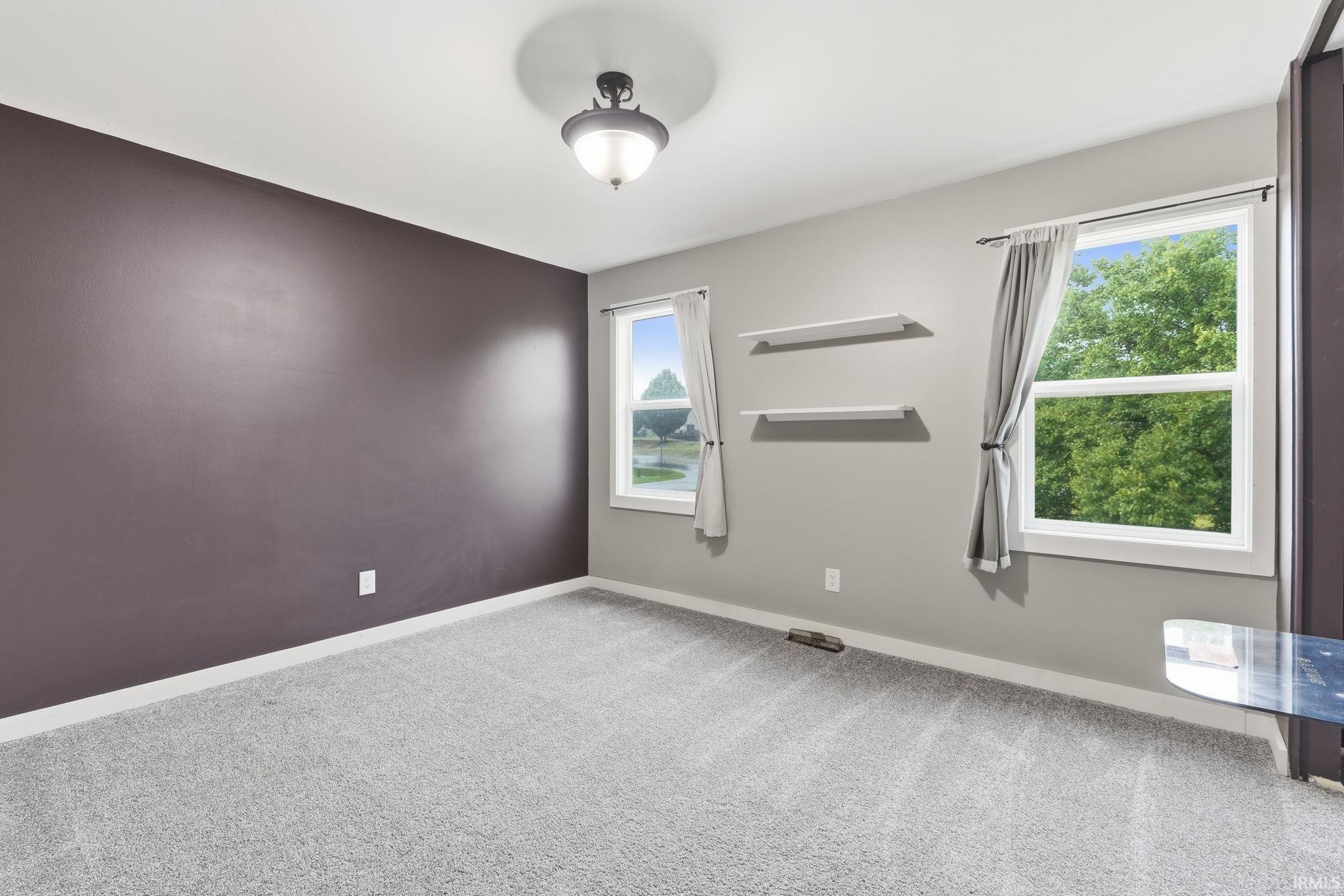 Plush carpeting, two double-hung windows, a semi-flush mount ceiling fixture, and a single accent wall
