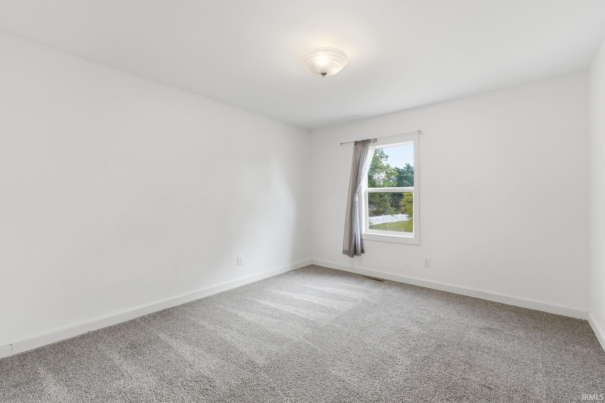 Neutral wall finishes with a ceiling-mounted light fixture, and a window