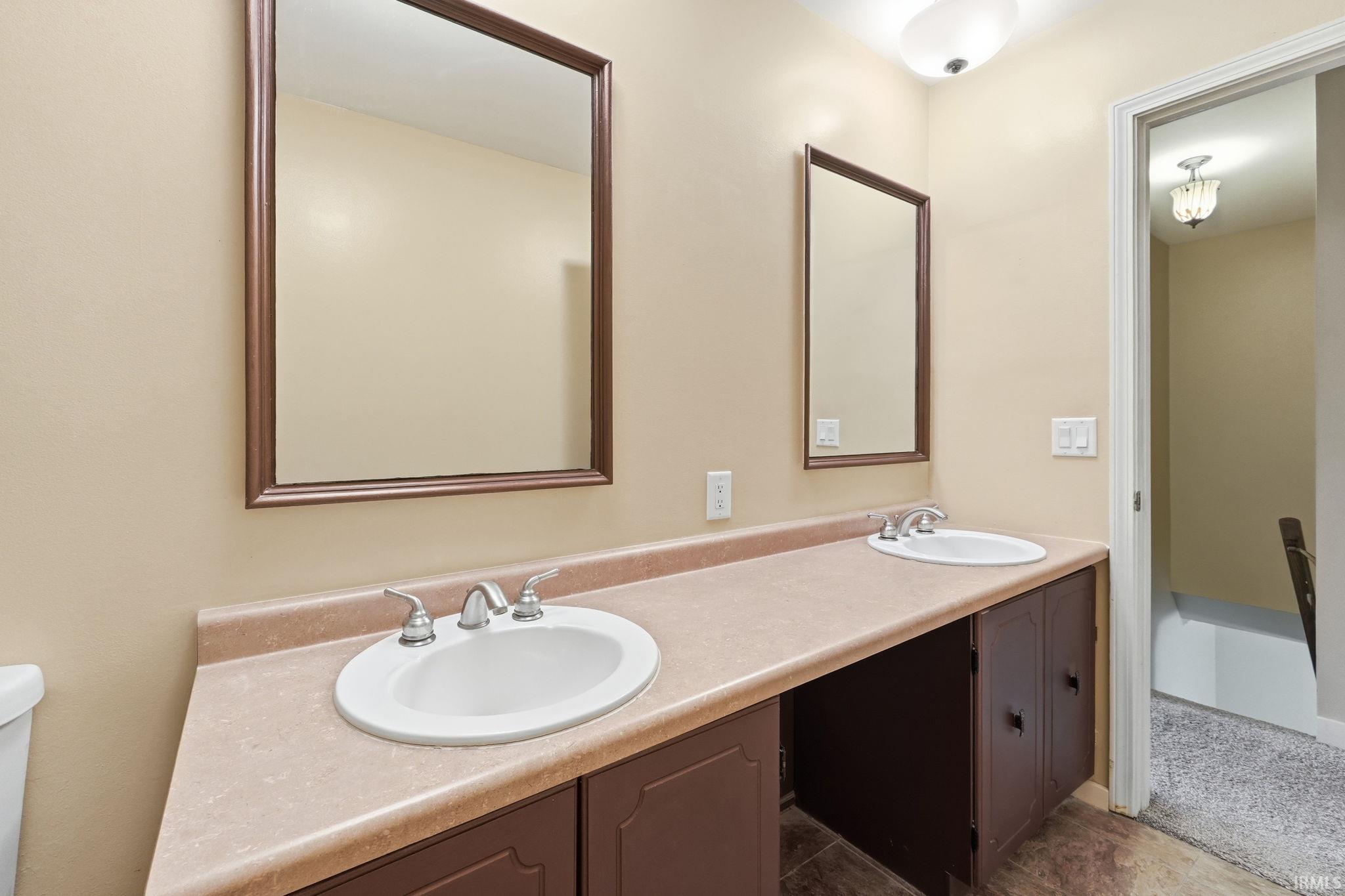 Dual vanity with integrated sinks, framed mirrors, and dark wood-finish cabinetry