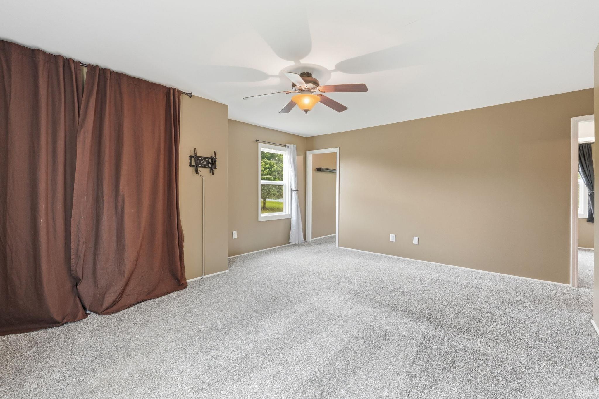 Expansive room with neutral tone walls and light gray carpeting