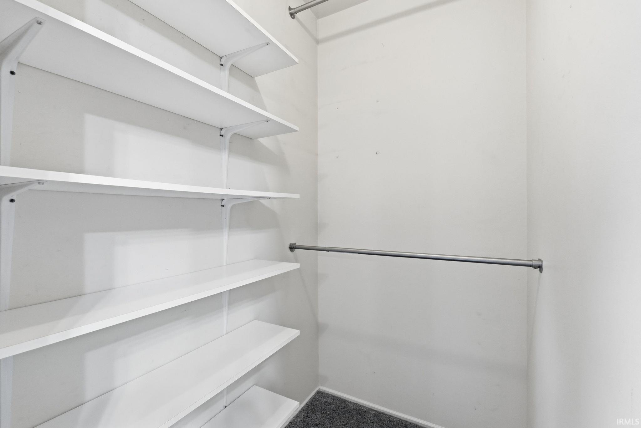 Built-in shelving with multiple white shelves and a chrome hanging rod