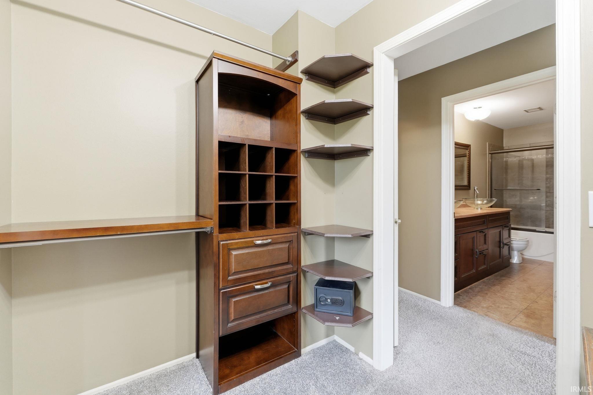Custom closet system featuring built-in shelving, drawers, and corner display shelves