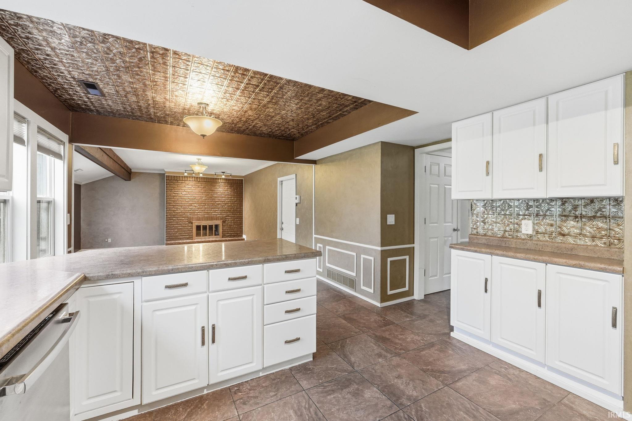White cabinetry with brushed nickel hardware, expansive countertop space, and patterned tile flooring