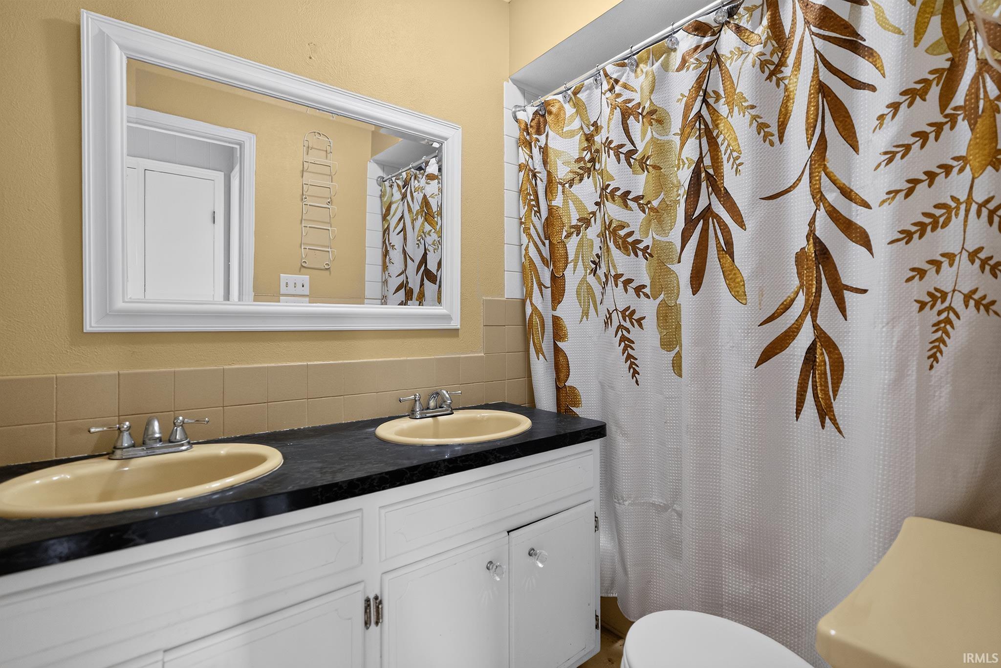 Dual vanity with undermount sinks, black countertop, and white cabinetry