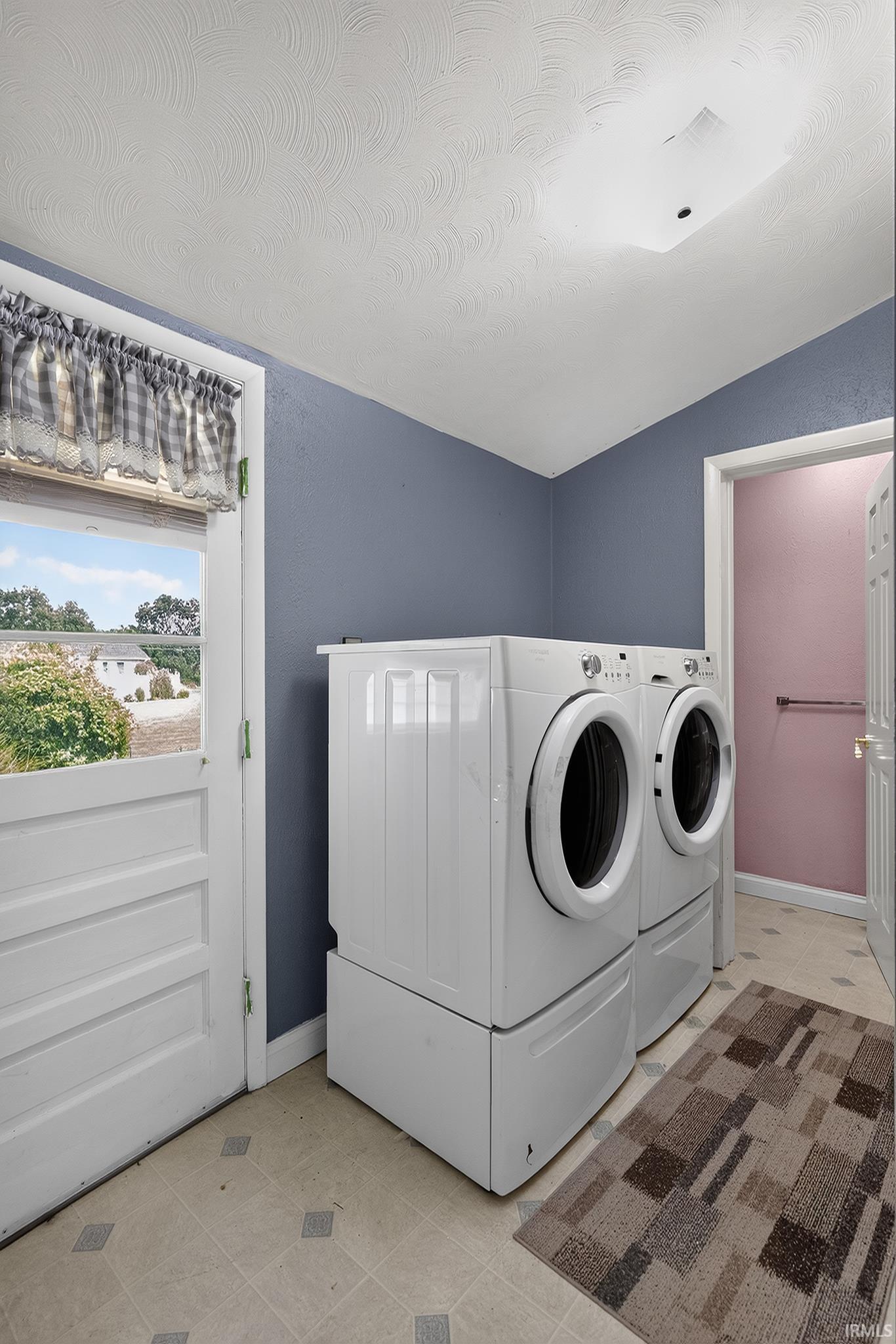 Dedicated laundry area featuring a Dutch door, patterned vinyl flooring, and a flush-mount ceiling light