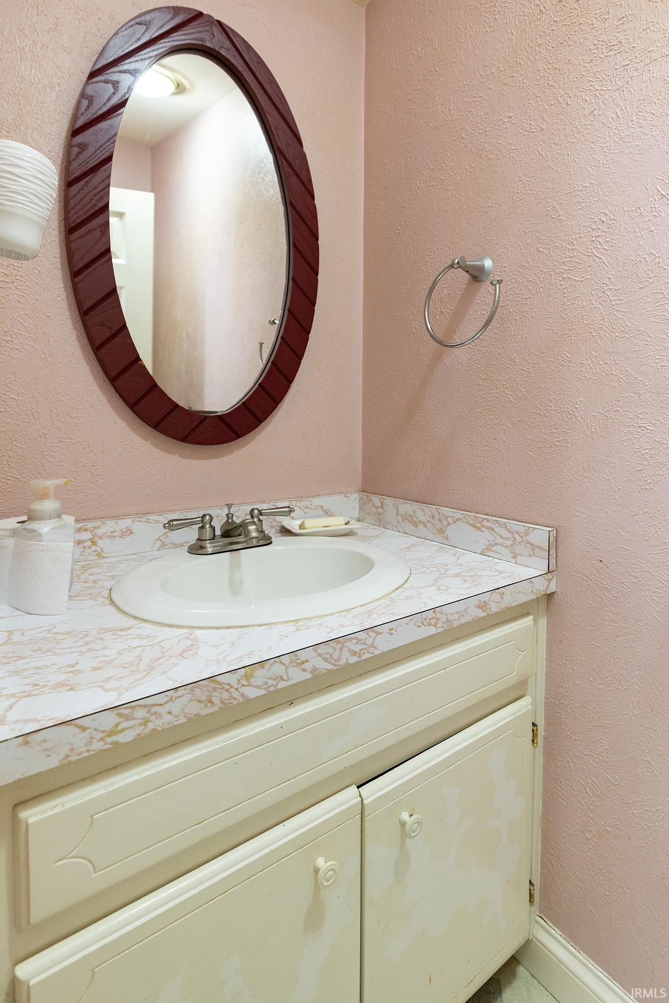 White vanity with decorative cabinet doors, integrated sink, and brushed nickel faucet