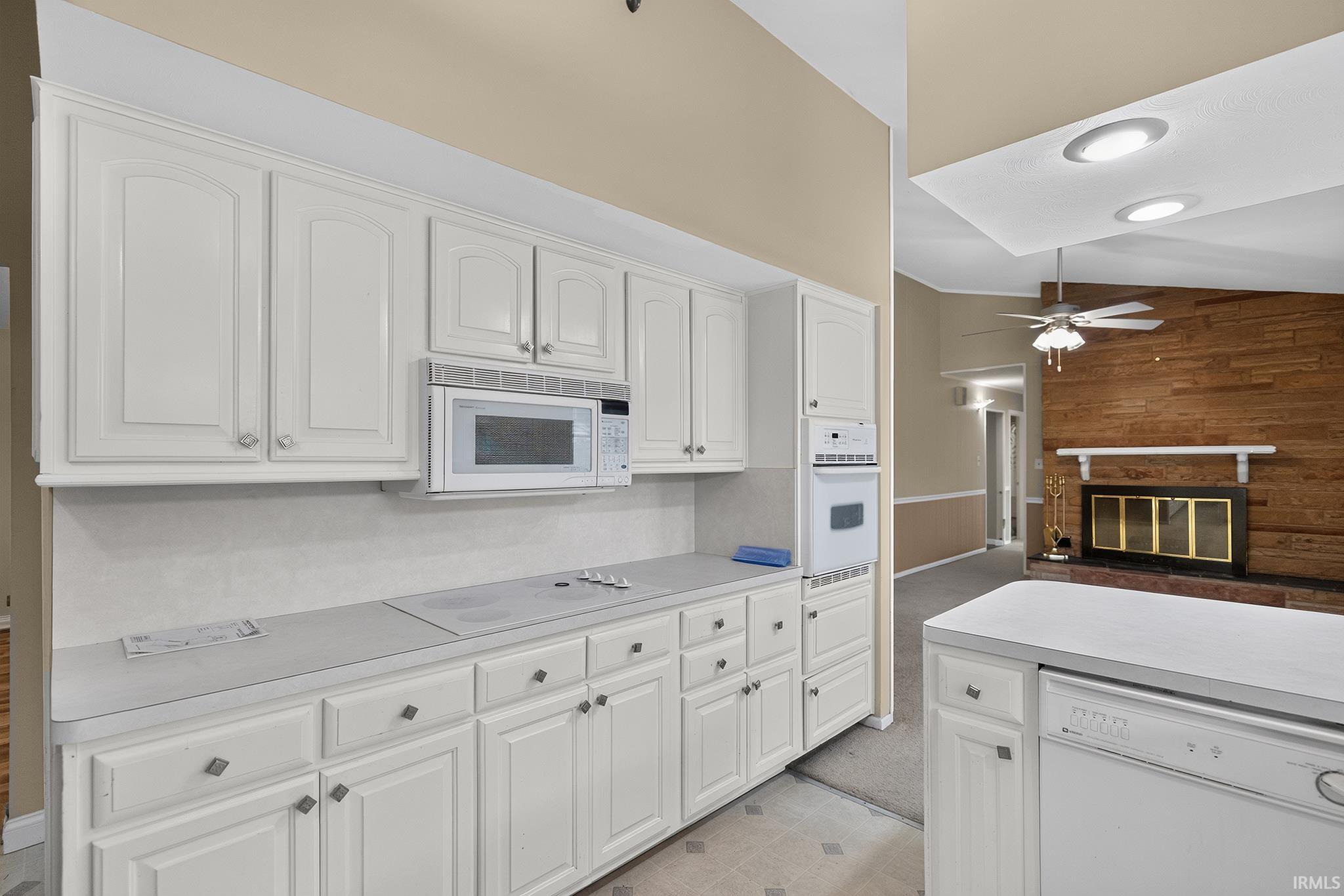 Kitchen featuring white cabinetry, built-in microwave, integrated wall oven, and a built-in dishwasher