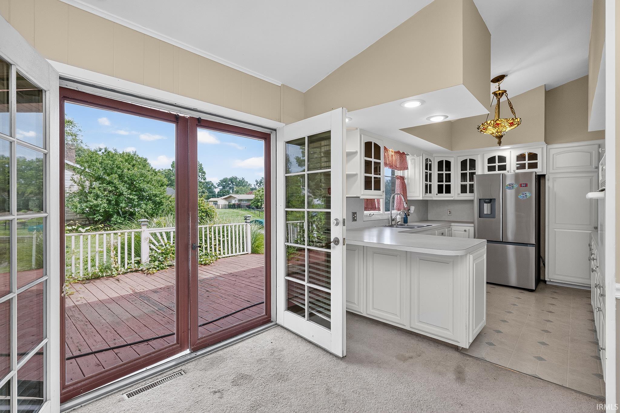 Kitchen with white cabinetry, stainless steel refrigerator, and a vaulted ceiling