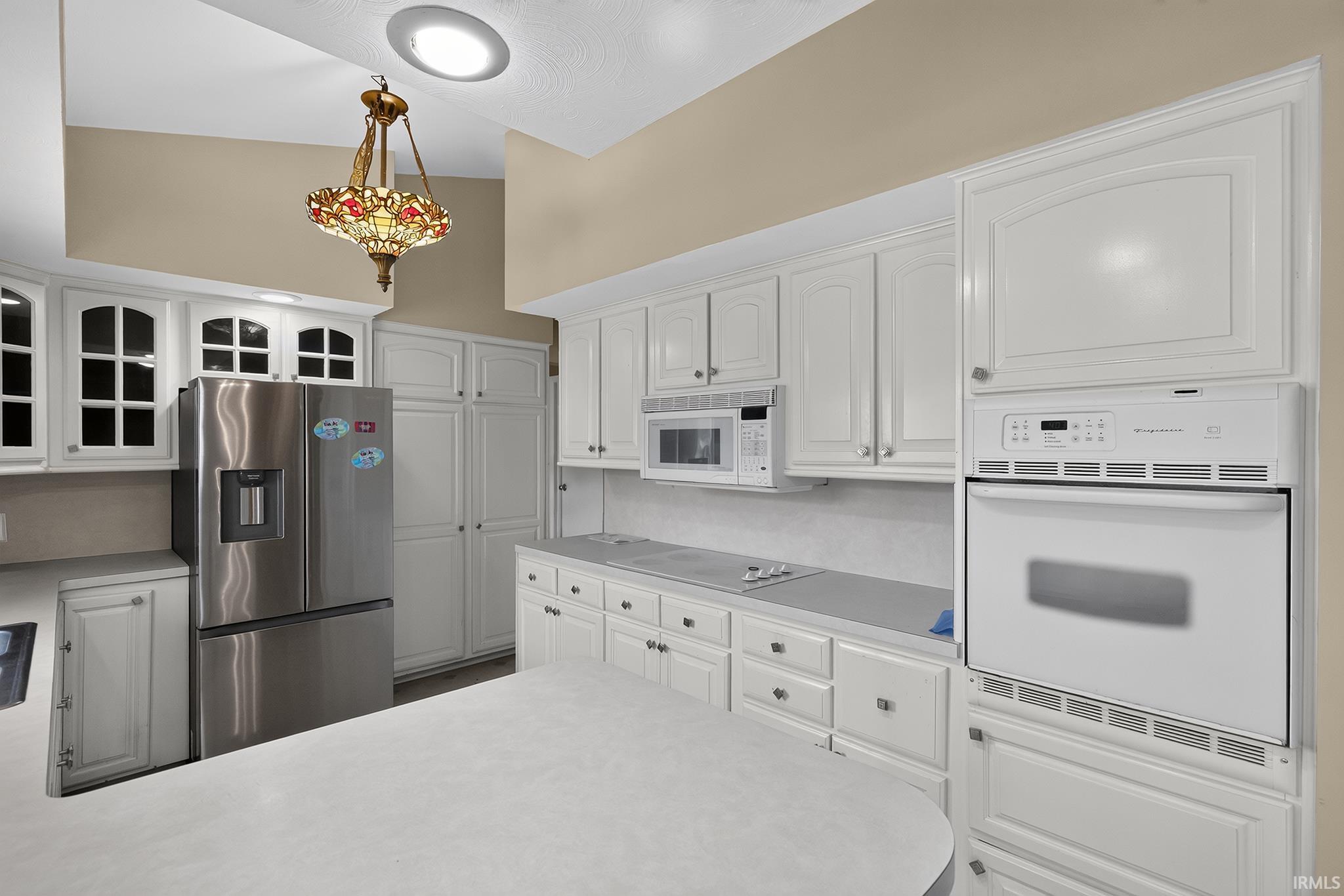 White cabinetry, stainless steel refrigerator, built-in microwave, integrated wall oven, and recessed ceiling lighting