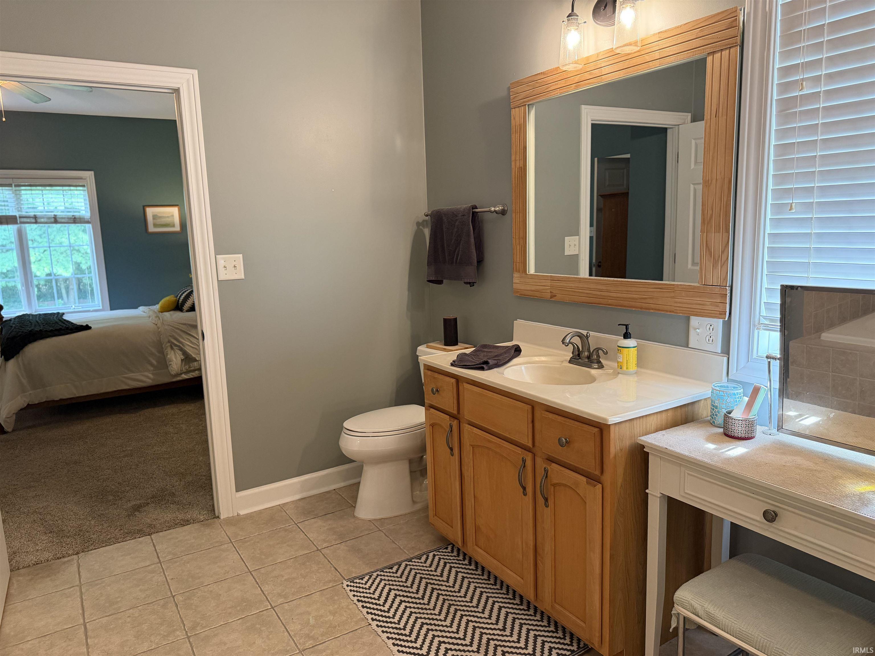 Bathroom vanity featuring a light wood-finish cabinet with double doors, a white countertop, and an undermount sink