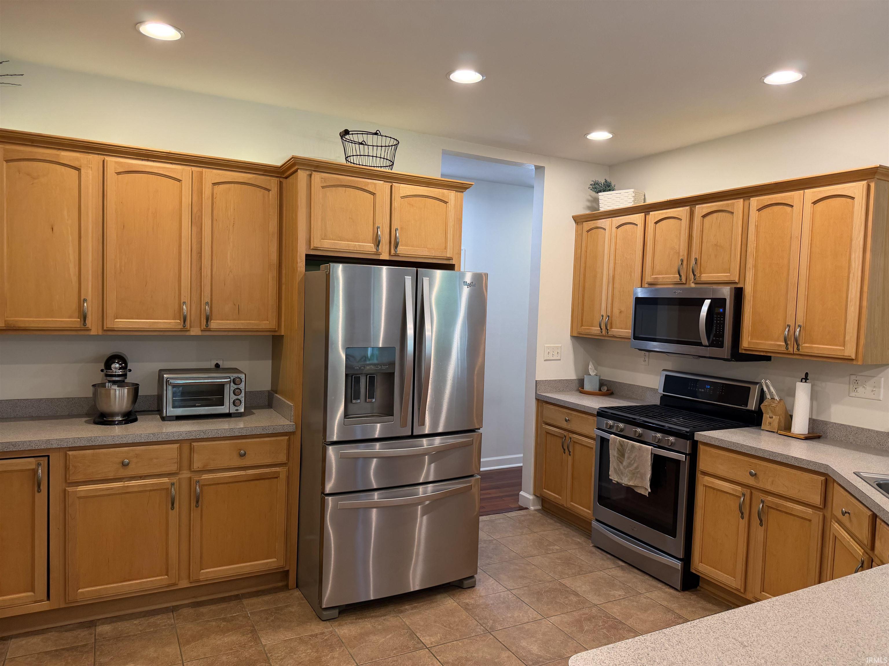 Kitchen featuring wood cabinetry, stainless steel appliances, recessed lighting, and tile flooring