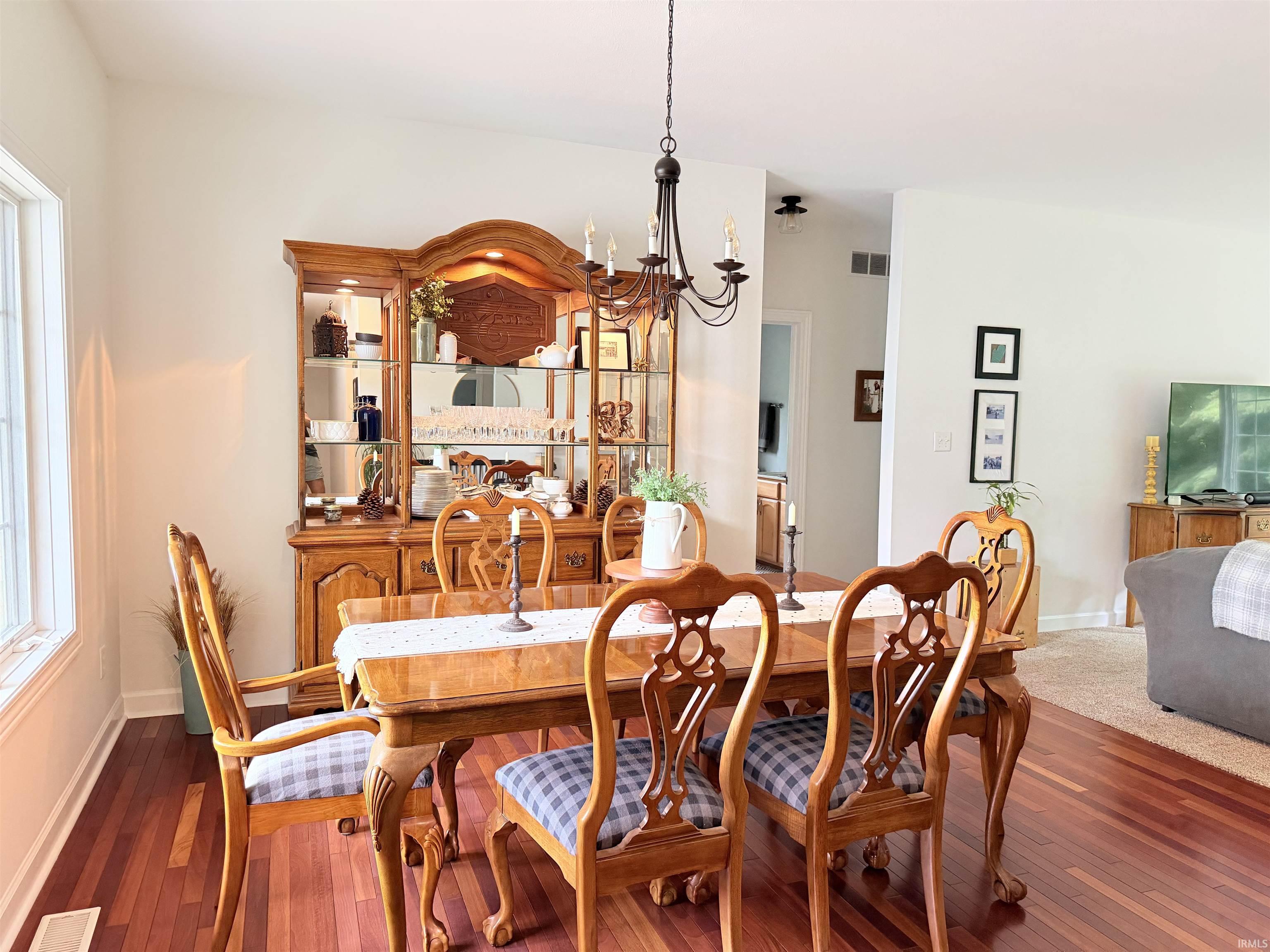 Dining area featuring hardwood flooring, a multi-pane window, and a chandelier