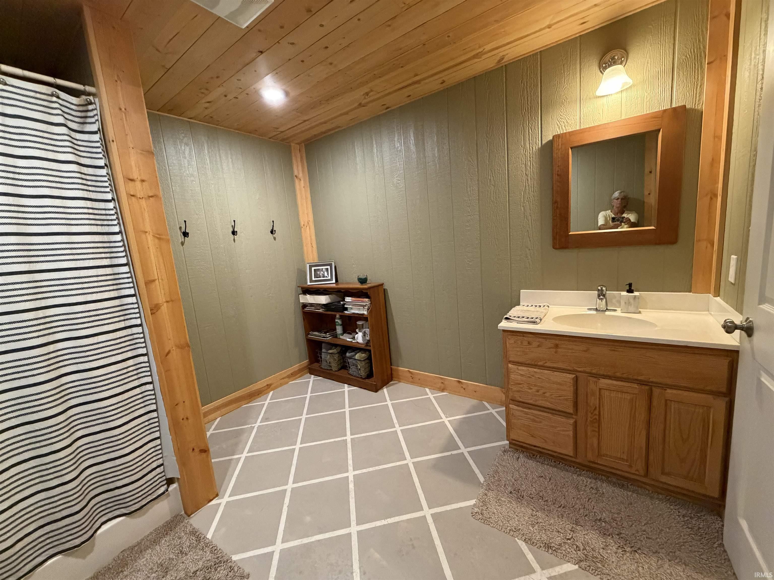 Bathroom featuring a single vanity with a laminate countertop, wood-finish cabinetry, and a framed mirror