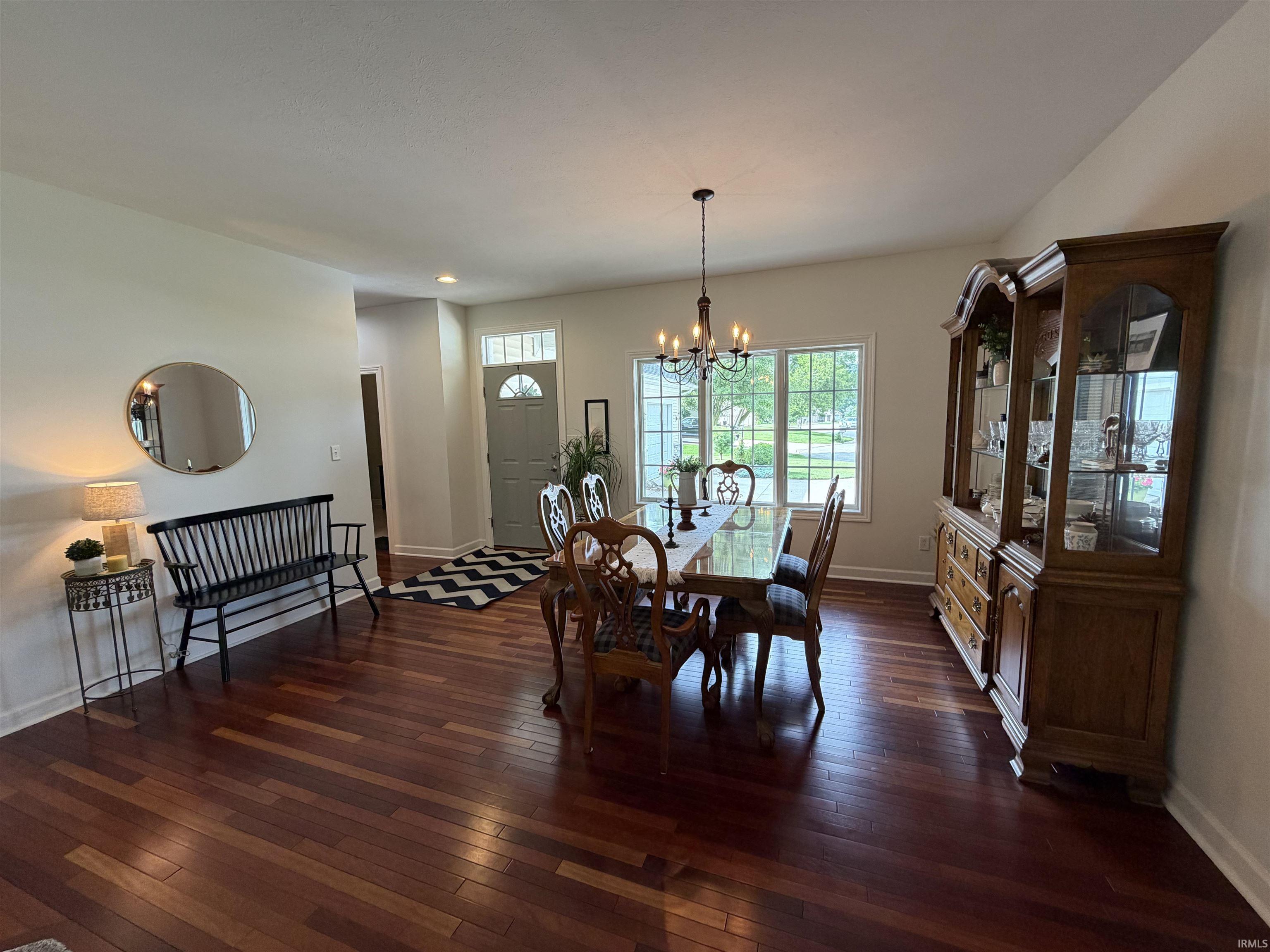 Formal dining area featuring rich wood-finish flooring, a multi-pane window, and a chandelier with candelabra lights