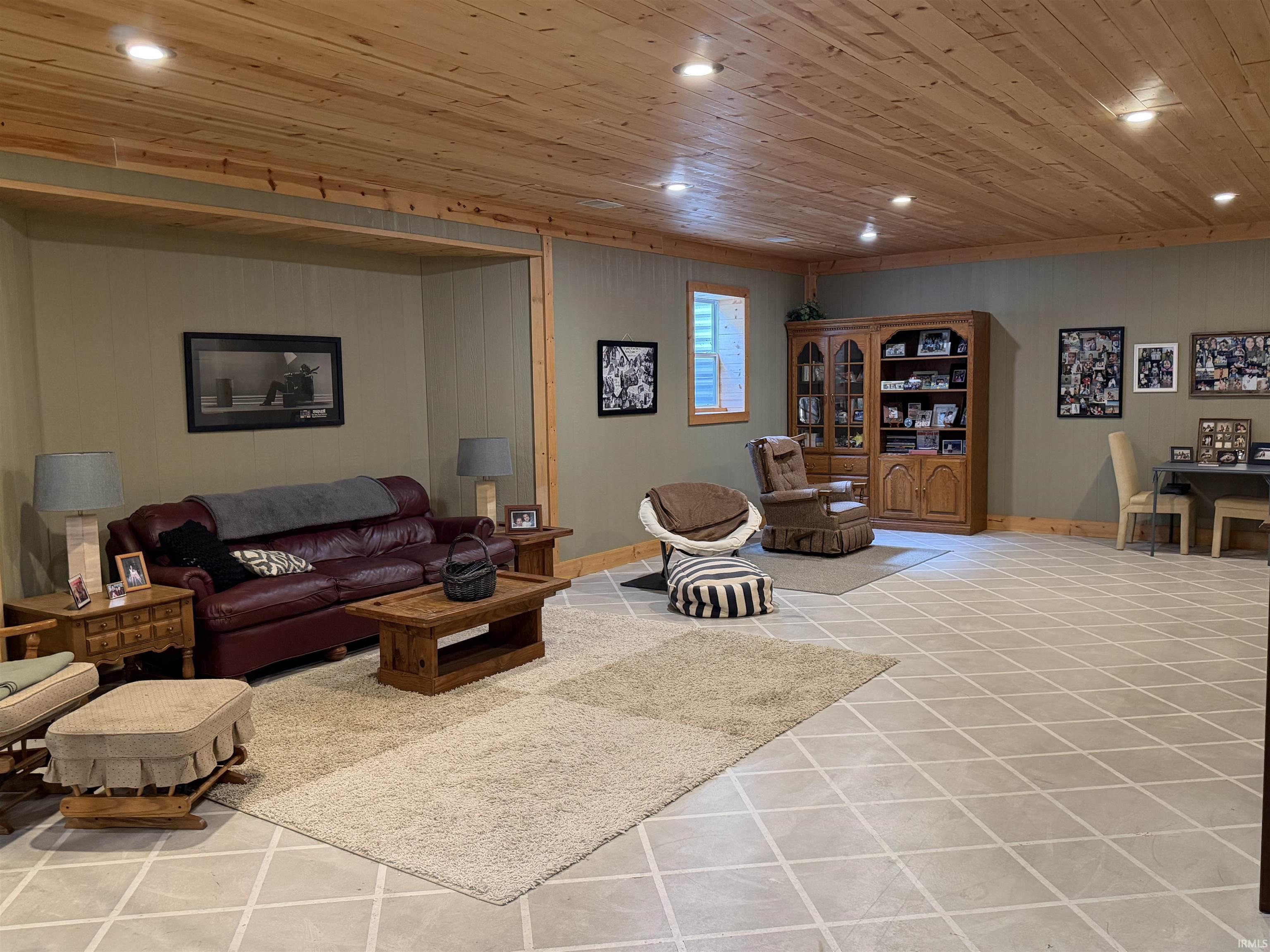 Spacious room featuring a wood-finish plank ceiling with recessed lighting, light-toned wall paneling, and a diamond-patterned tile floor
