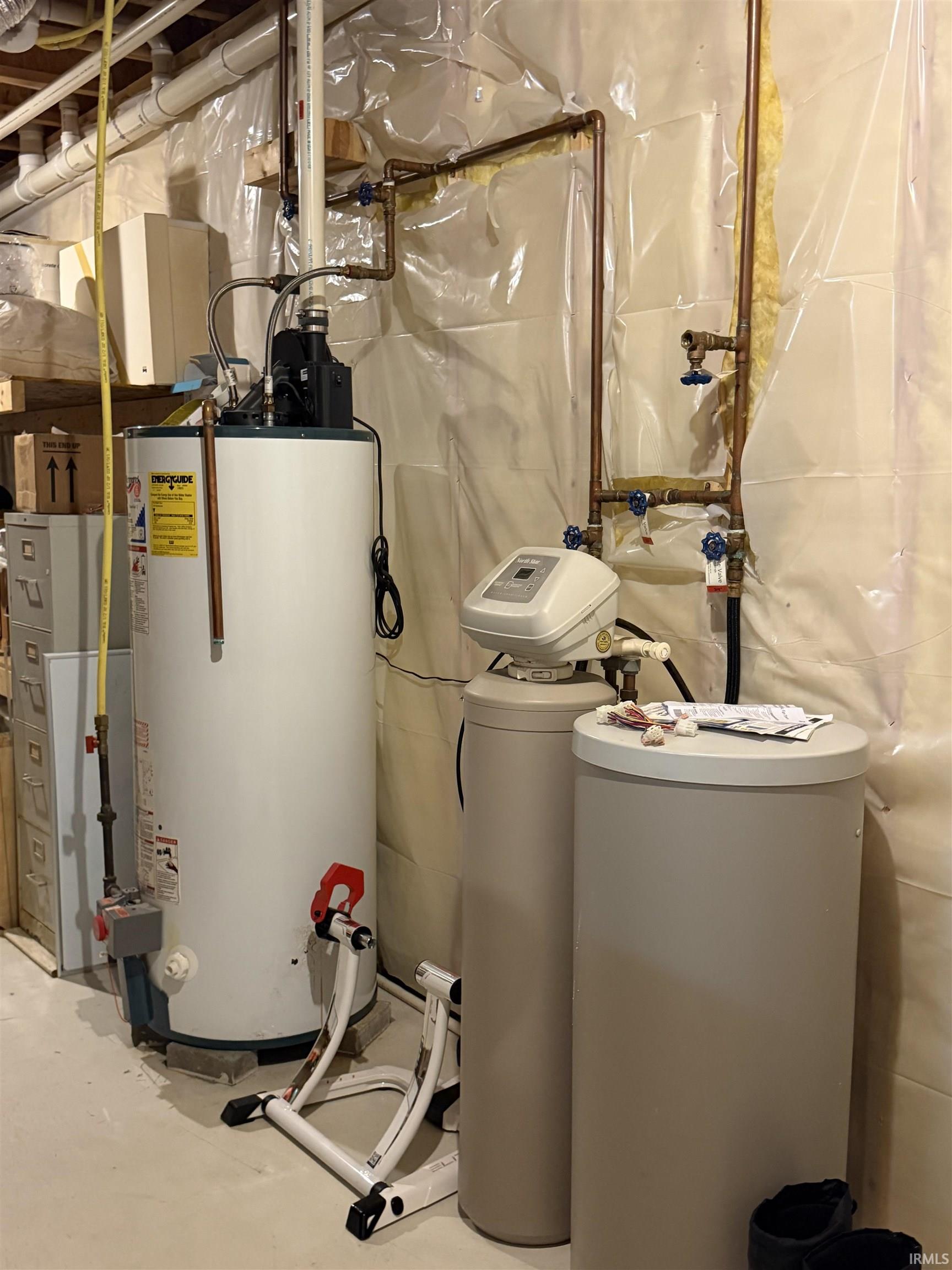 Utility area featuring a large water heater, copper piping, and a water treatment system